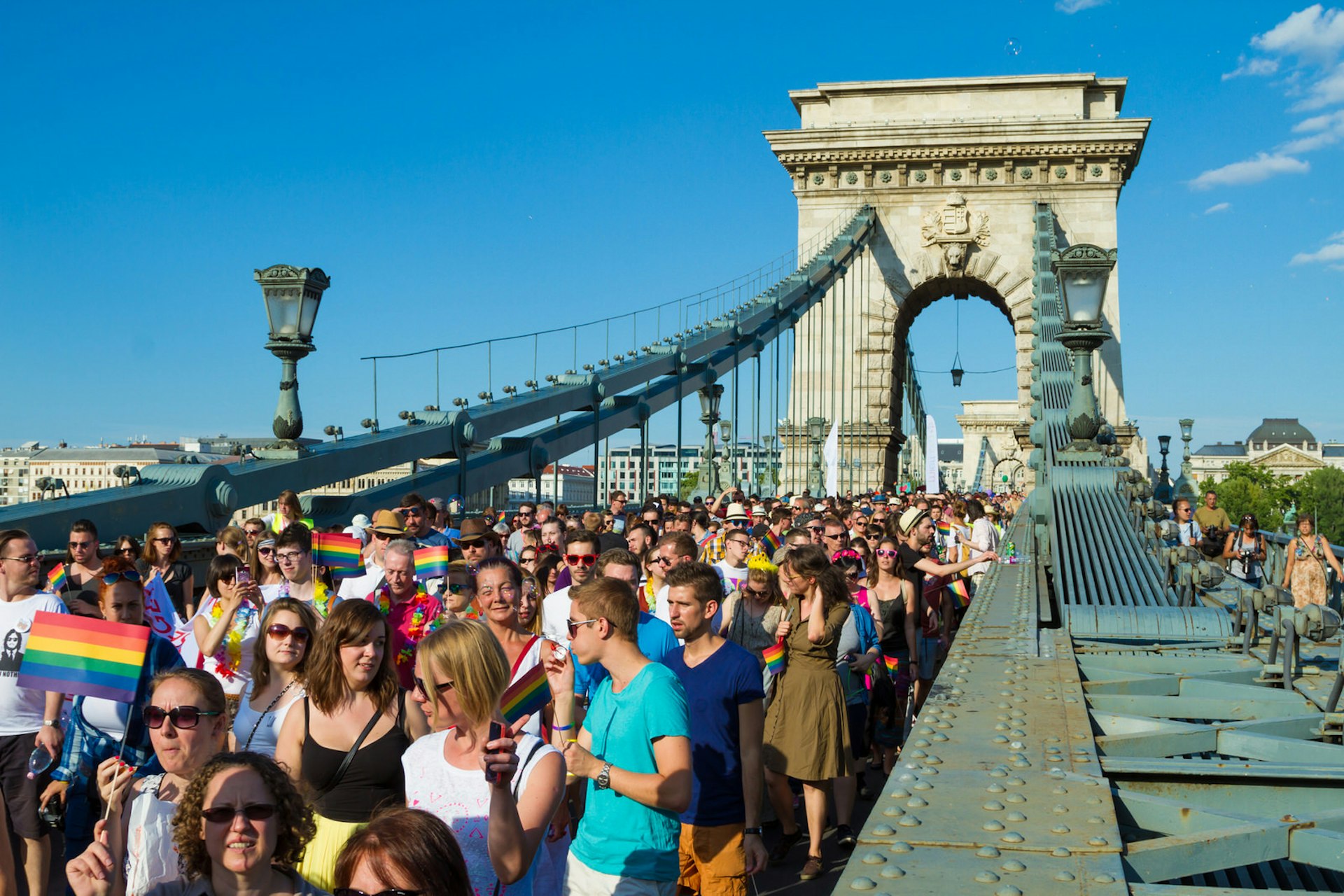 Pride in Europe: A crowd of Pride-goers on a bridge under blue skies in Budapest © conejota / Shutterstock