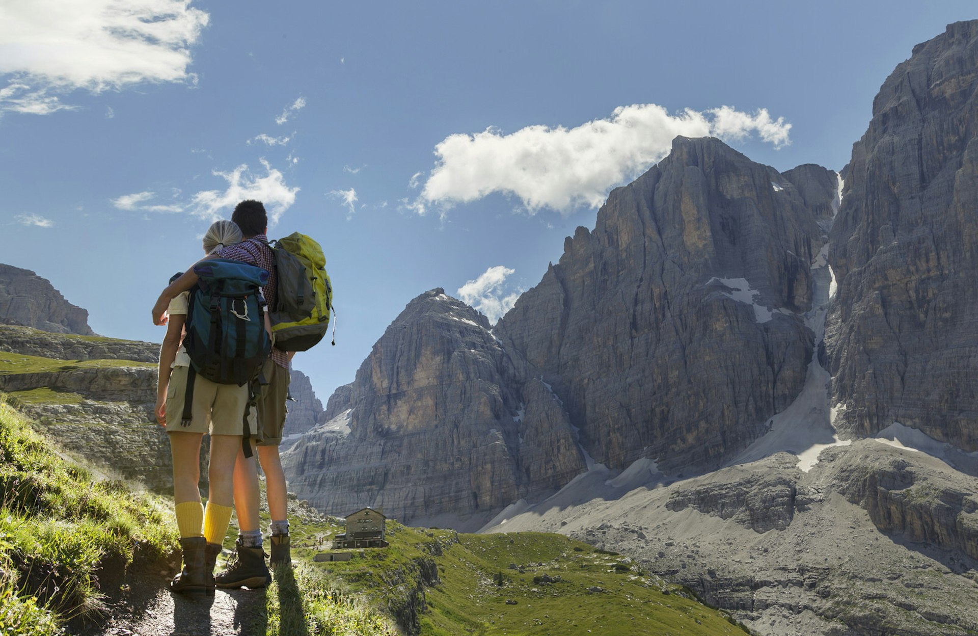 A hiking couple gazes towards a dramatic rocky outcrop