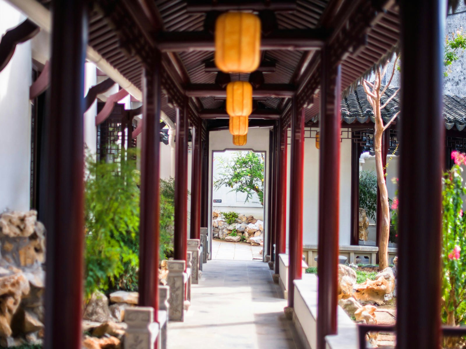 View down covered walkway with red wood posts and red lanterns. Pavilions and covered walkways allow gardens to be enjoyed year-round © HelloRF Zcool / Shutterstock