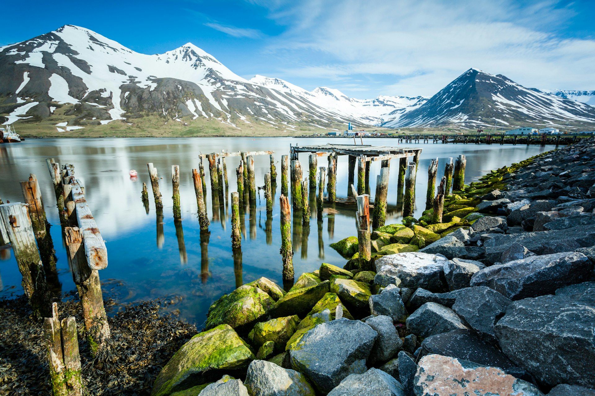 old-piles-are-all-that-remain-of-an-old-fishing-pier-in-the-harbour-of-Siglufjörður-blue-sky-snow-capped-mountains-in-background © Pall Jokull / www.flickr.com / photos / palljokull / Getty Images