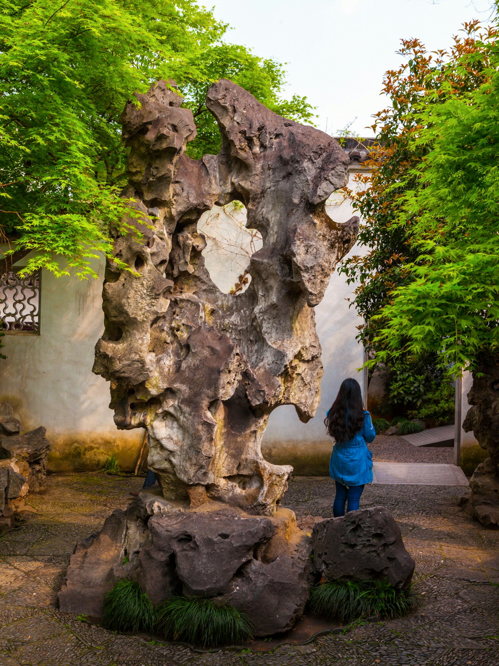 A large, gnarled rock formation with a hole in the middle. The Garden to Linger In is a good place to see giant, bizarrely shaped rock stele © Meiqianbao / Shutterstock