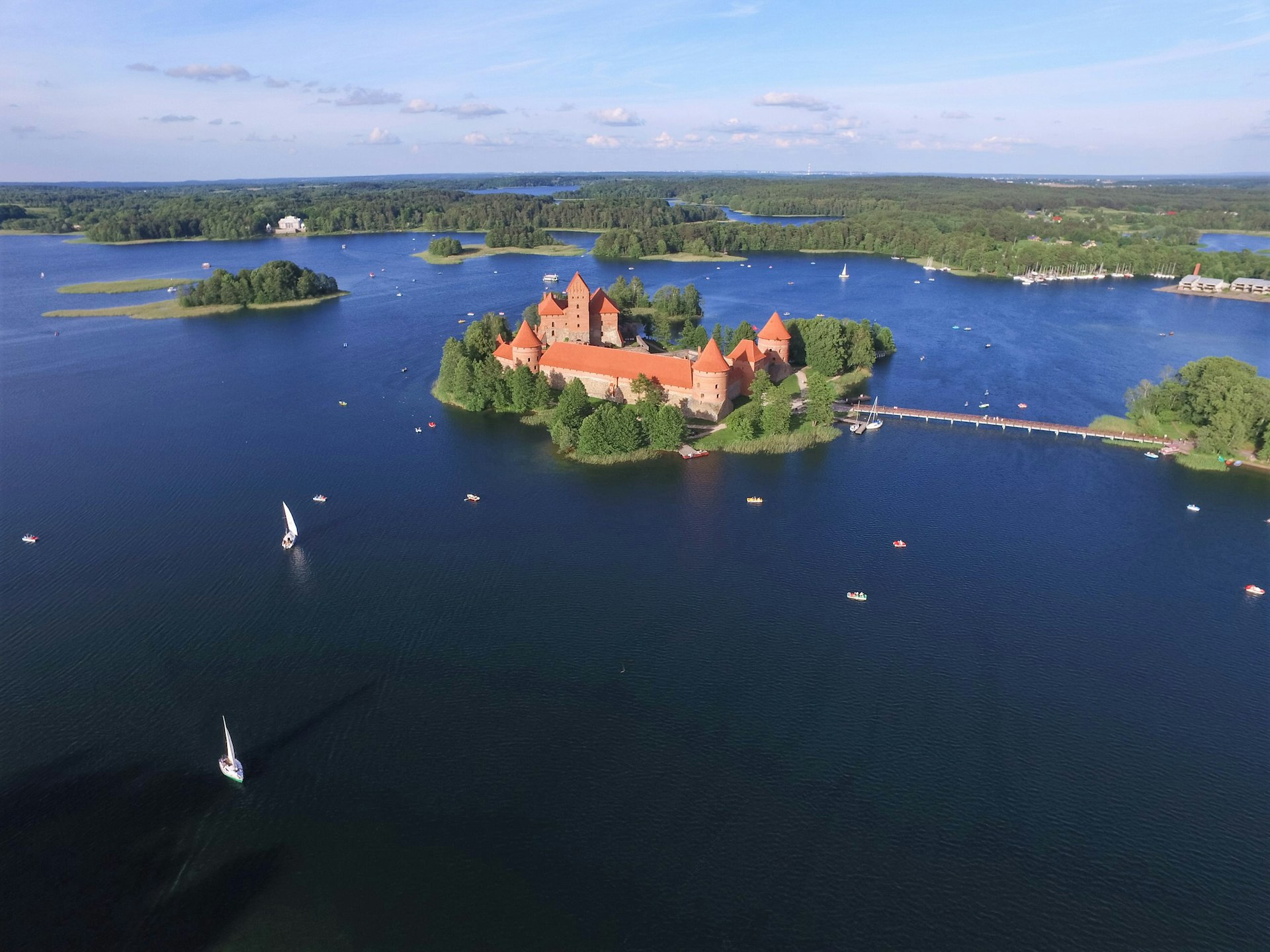 Aerial view of Trakai Island Castle, with small boats sailing in the surrounding lake © Audrius Merfeldas / Shutterstock