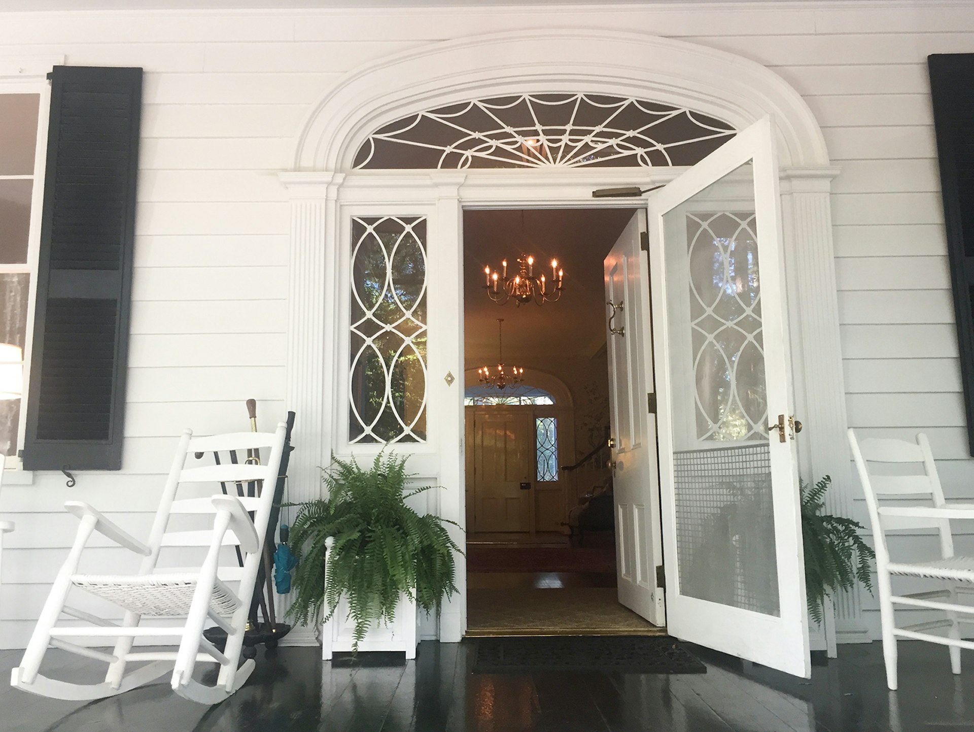 a small fern and a rocking chair next to the open front door of an antebellum home in Augusta Georgia