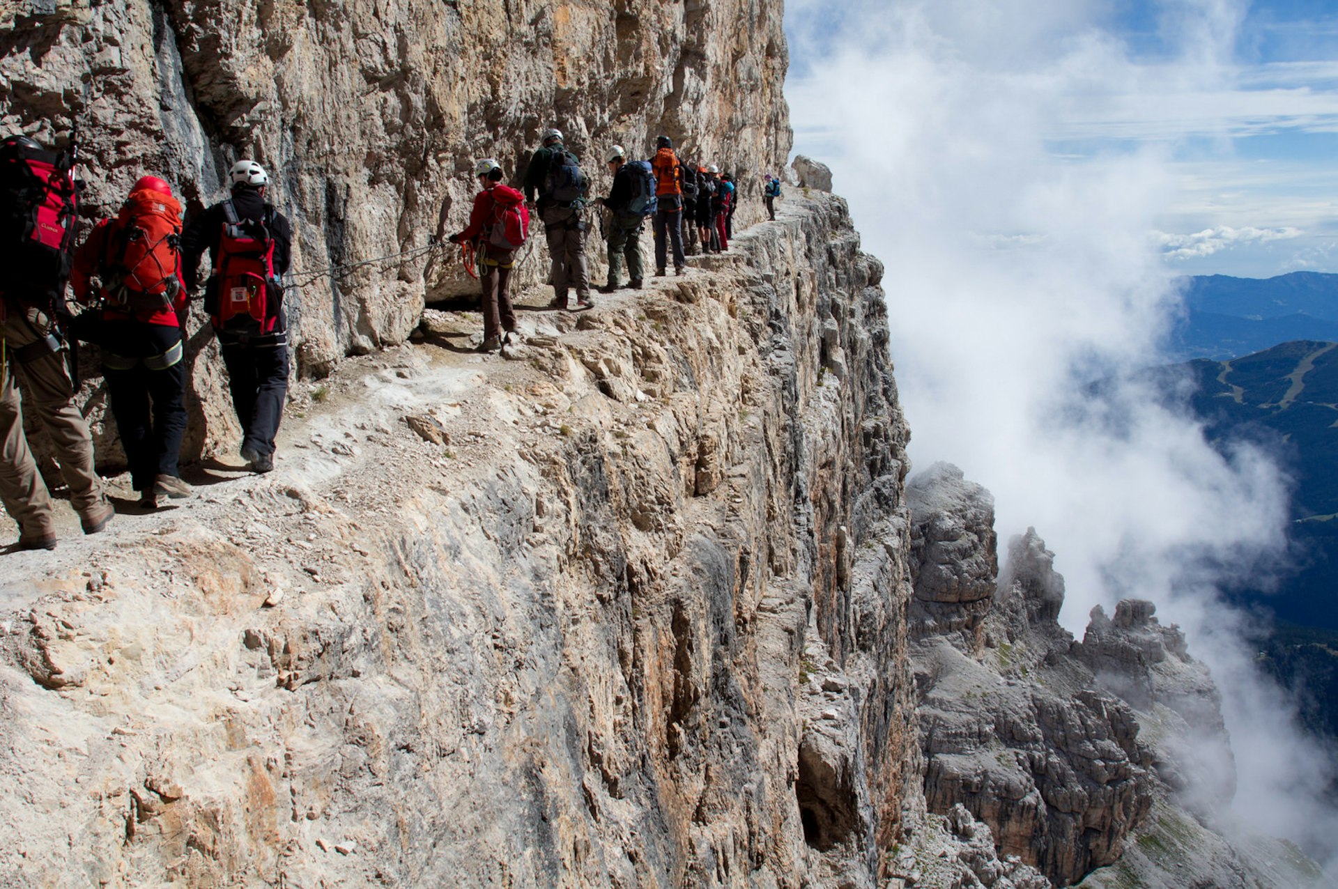 A group of climbers on a via ferrara edge their way past a precipitous drop