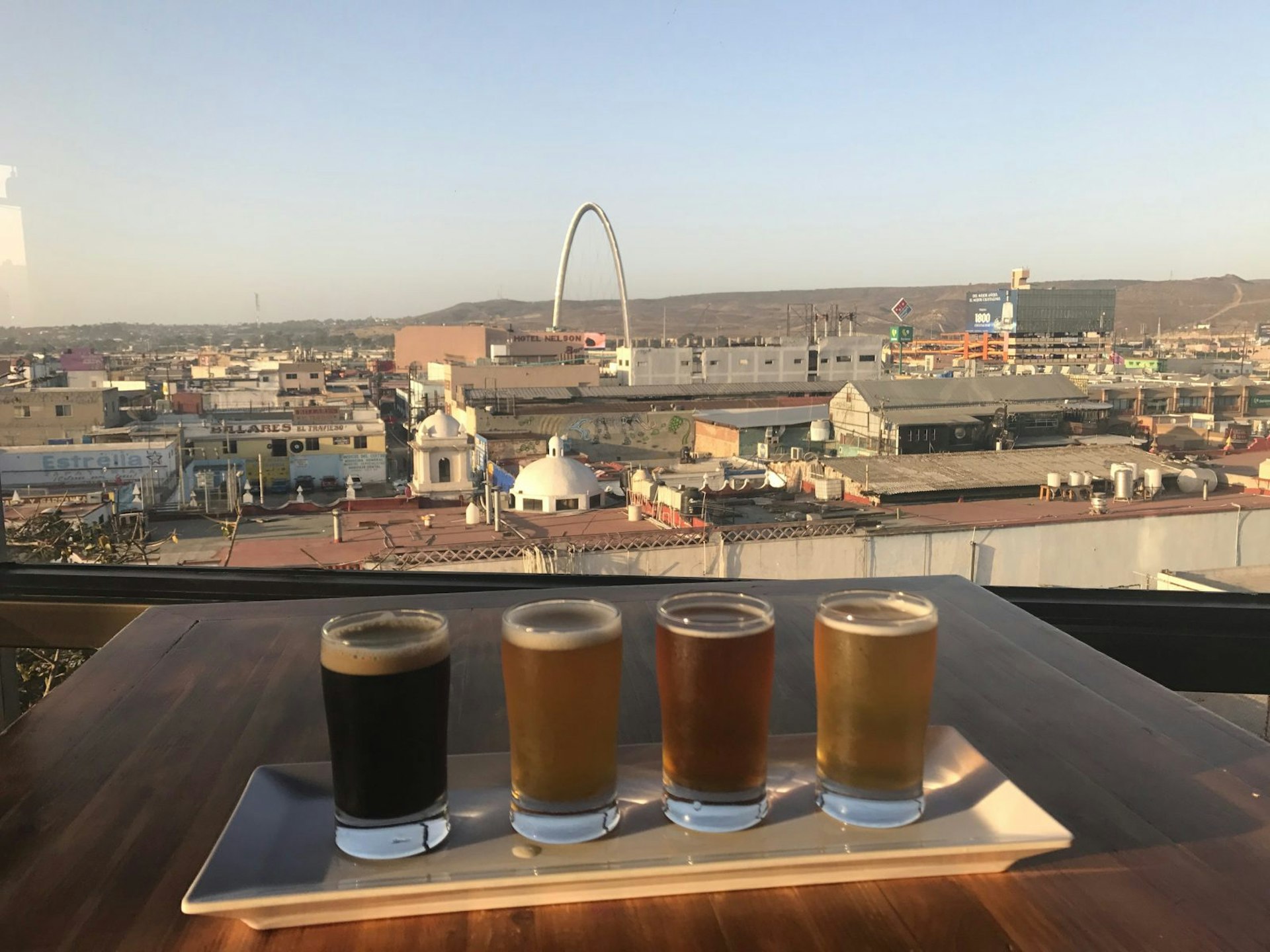 A flight of craft beer sits on a ledge overlooking the city of Tijuana on a clear day © Celeste Brash / Lonely Planet