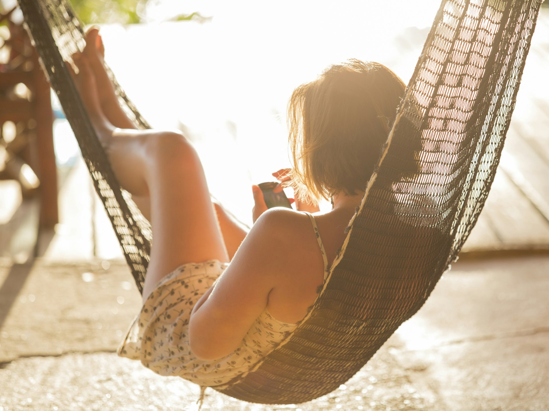 A woman relaxing in a hammock on her phone