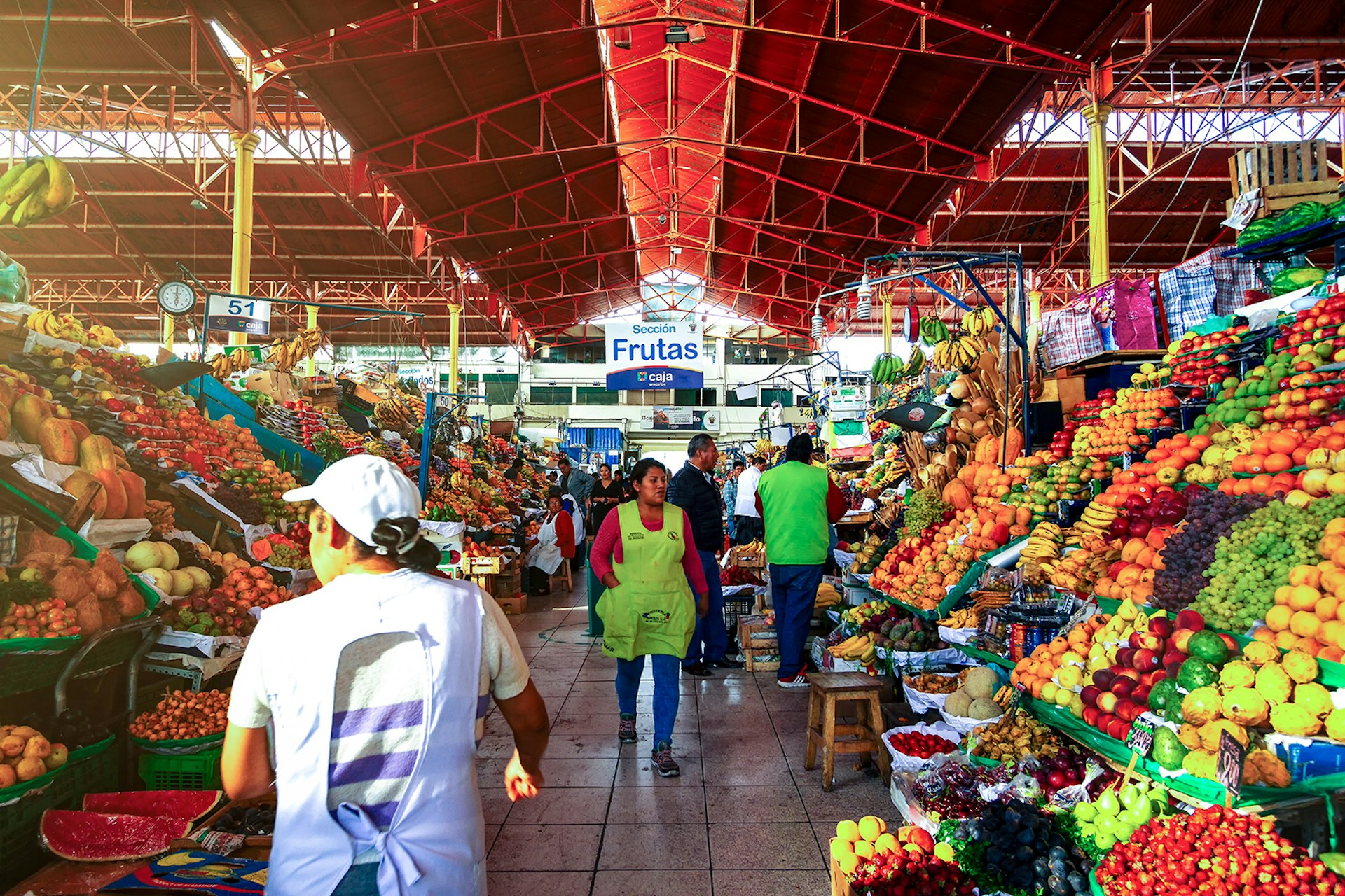 Features - Daily Image. Vendors go from one stall to another in the San Camilo market in the morning of Arequipa. Local people frequent the market daily to buy groceries, fabrics or food