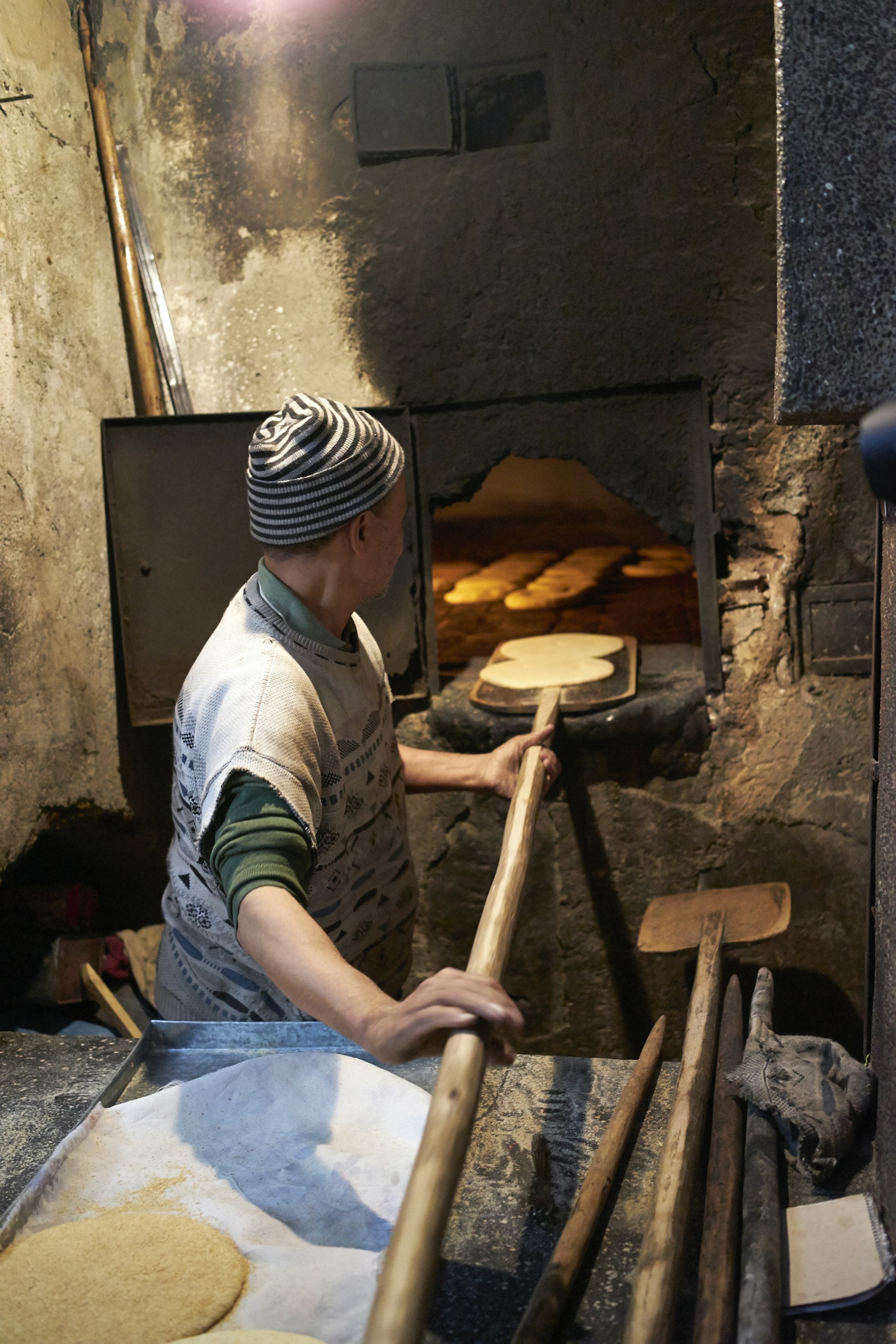 A man putting some bread into a traditional street oven in Fez, Morocco