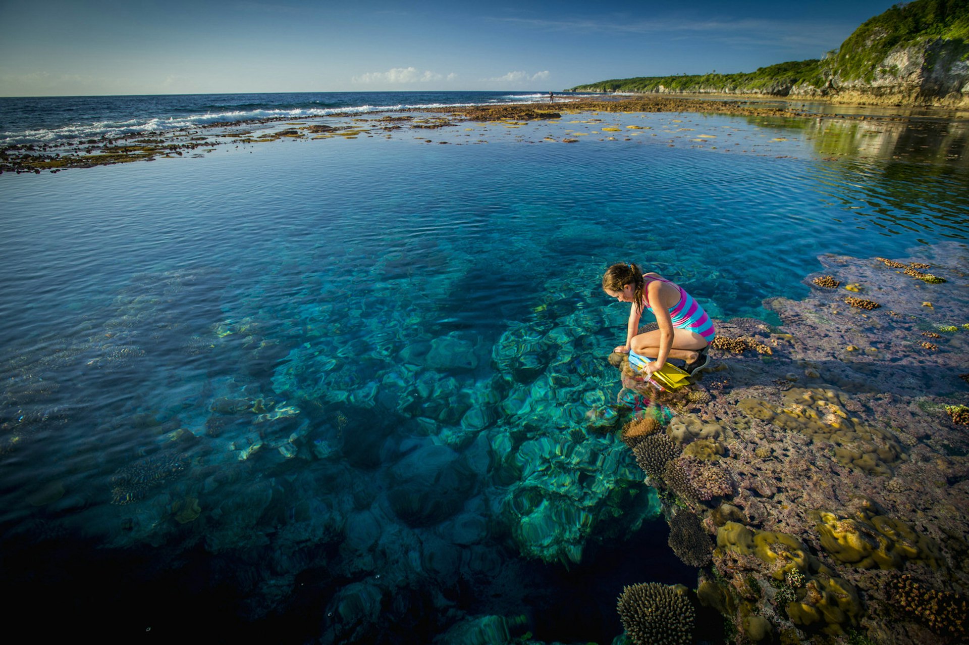 A girl looks into a rock pool in Samoa, South Pacific 