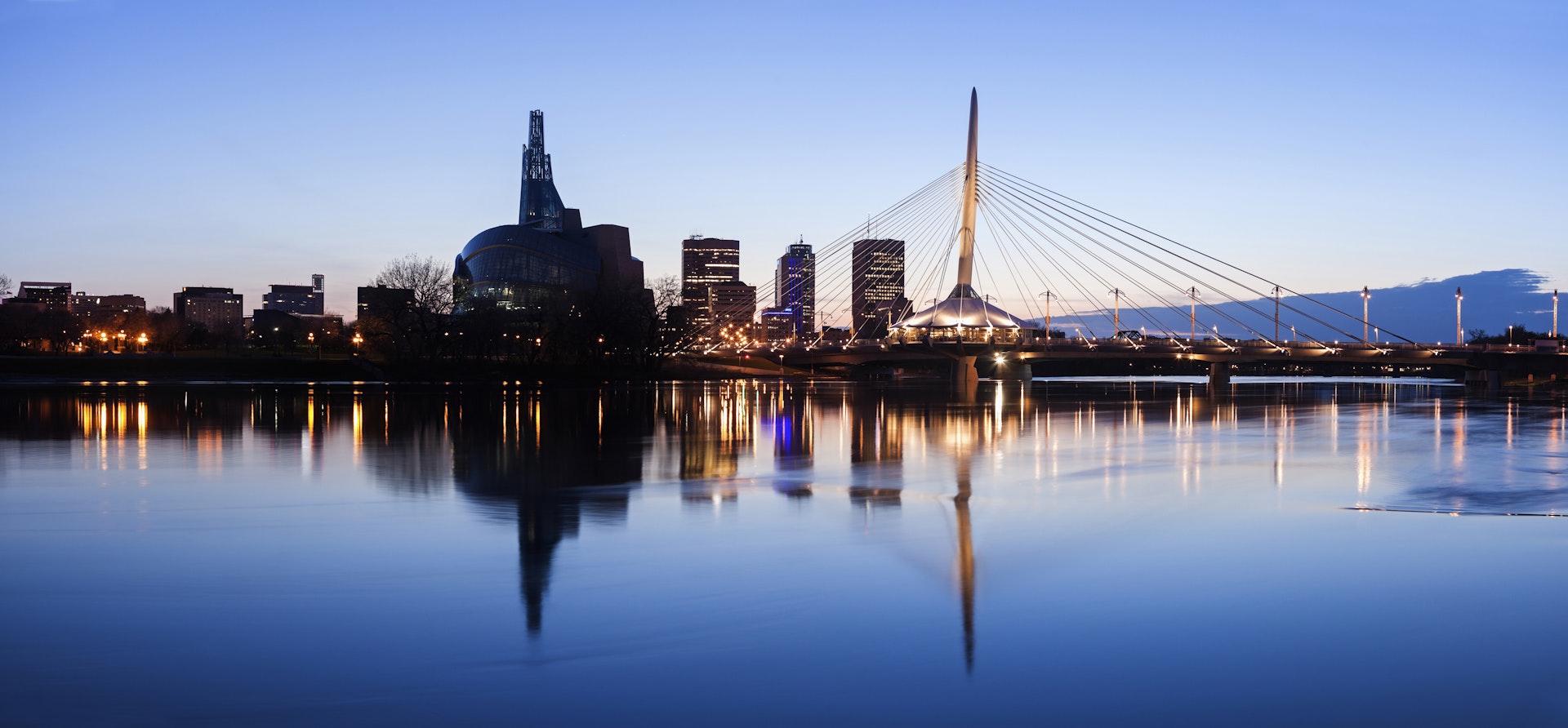 Features - Canada, Manitoba, Winnipeg, Illuminated skyline reflecting in calm Assiniboine River