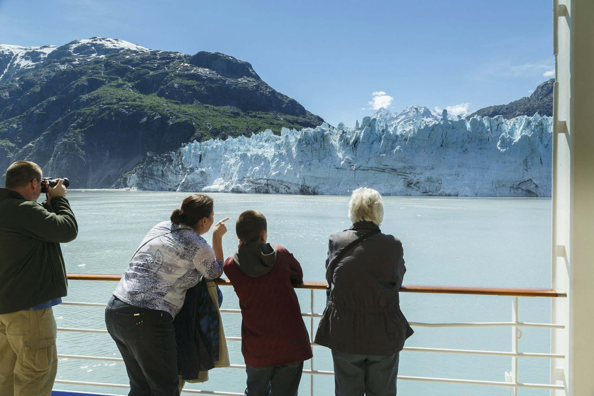 A family of varying ages enjoy the sight of a glacier during a cruise © Jeff Schultz / Getty