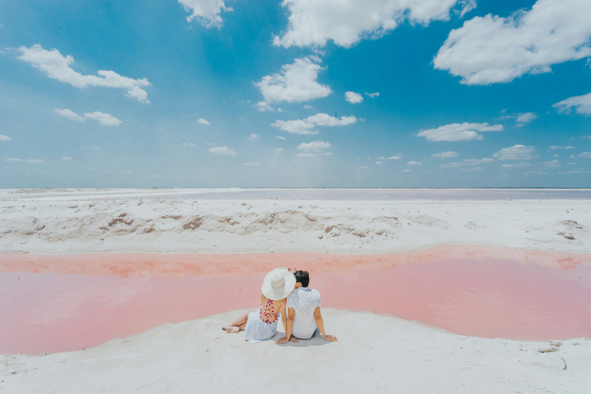 Minimoon magic: a couple sit next to the pink water of Las Coloradas, Mexico © jin chu ferrer / Getty