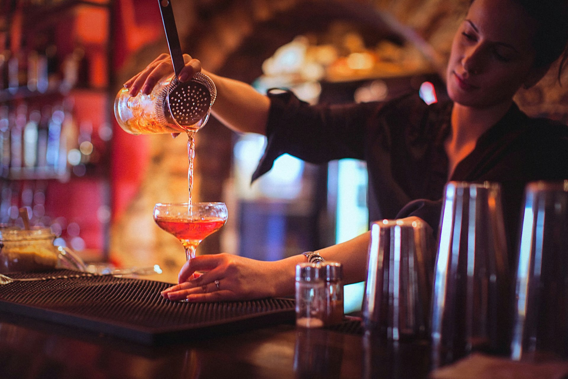 Young female bartender pouring cocktails in a cocktail bar © gruizza / Getty Images