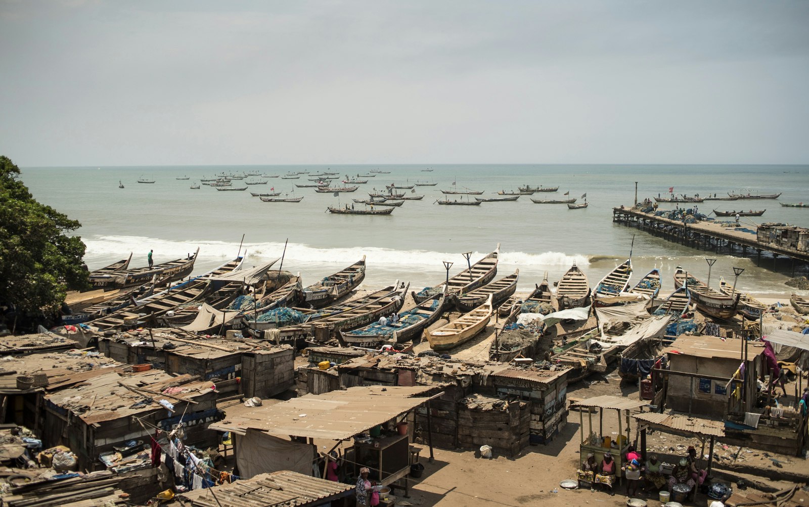 This image looks over a beach chalk full of traditional fishing boats to the sea and a distant horizon. Floating in the waer are also dozens of fishing boats © Elio Stamm / Lonely Planet