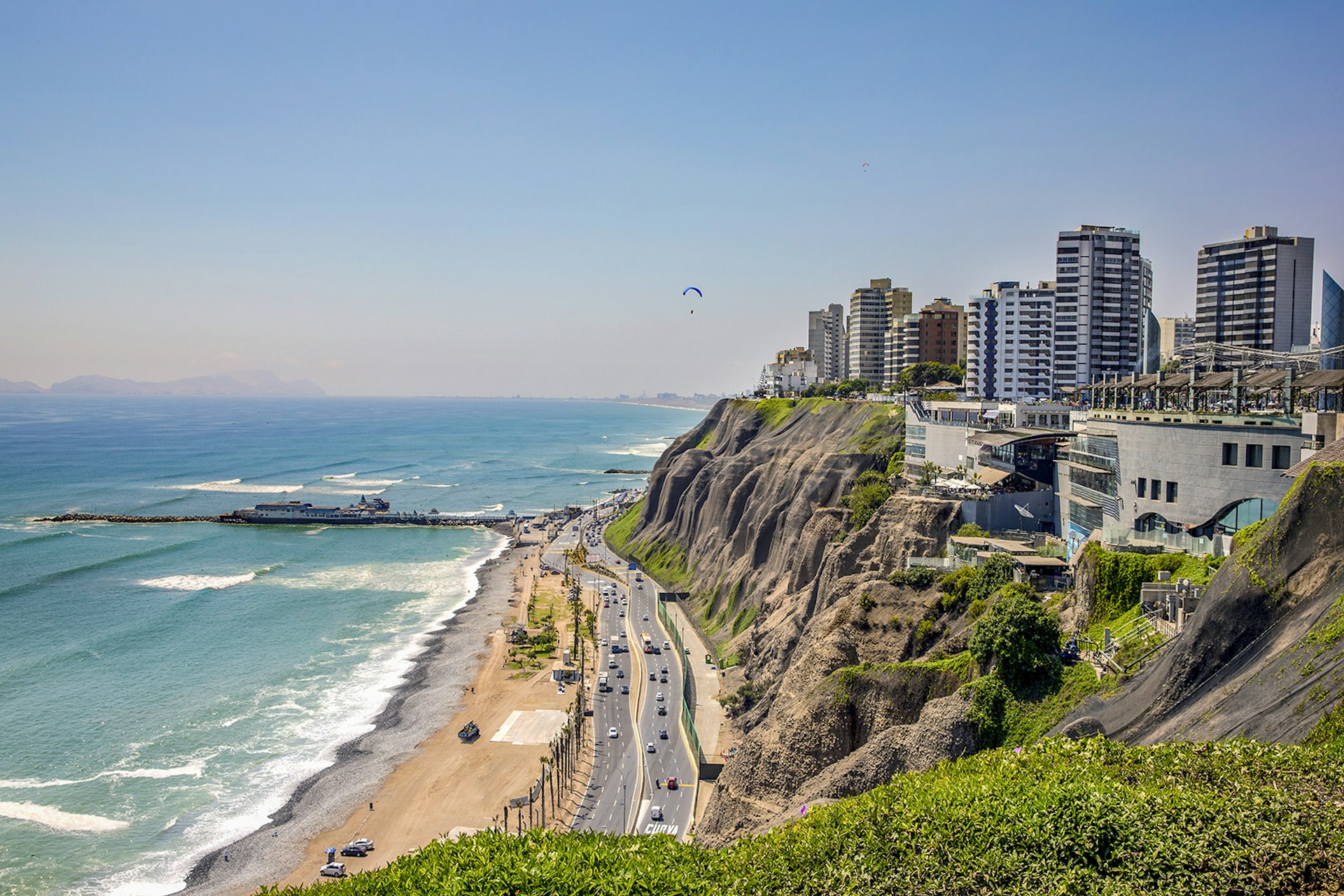 Aerial view of the coastline in Lima with a paraglider in the sky