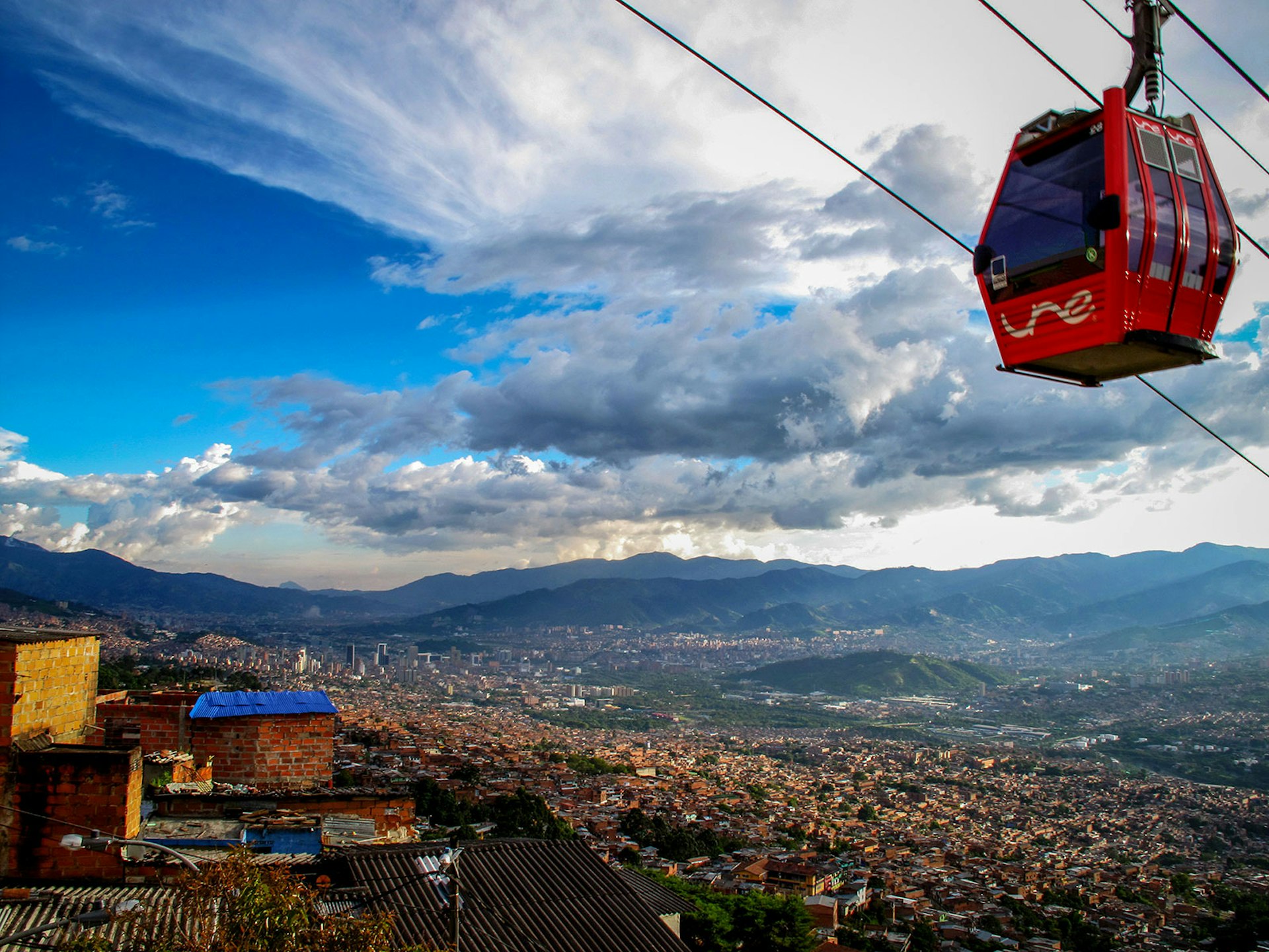 A cablecar passes over a hillside neighborhood of Medellín