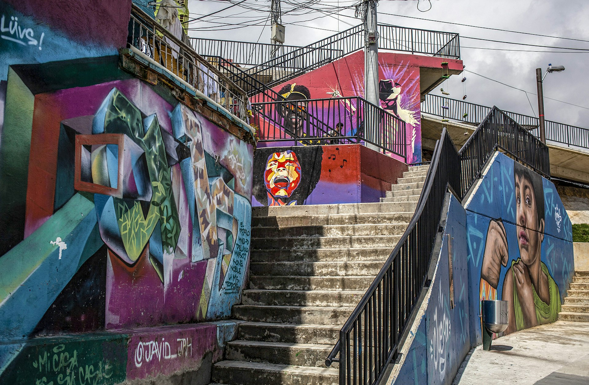 Street art murals cover concrete walls around in a stairway in Medellín