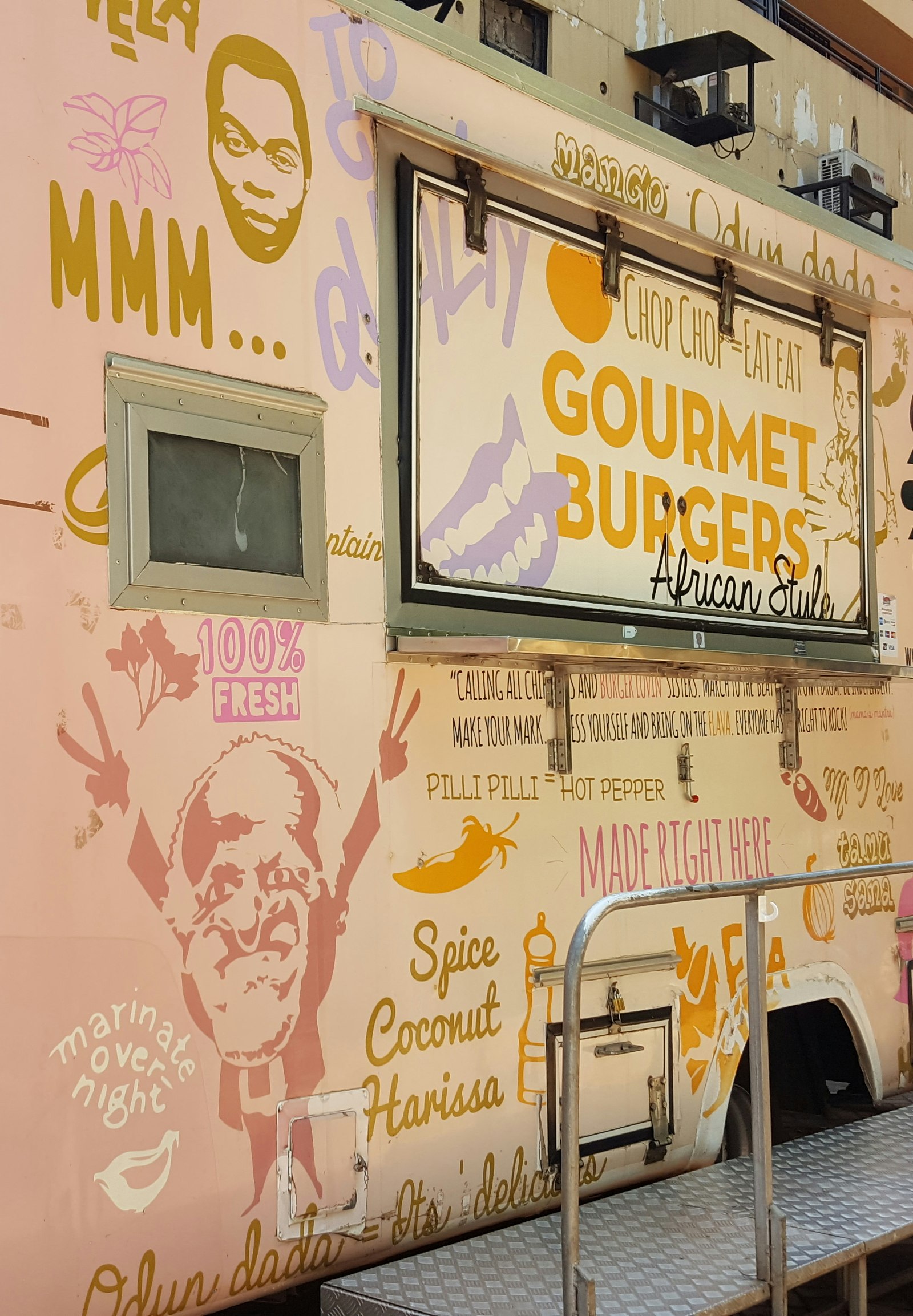The Mama Rocks food truck sits with its service window closed. The back portion of the truck is covered in monochomatic images and text, calling out dishes like gourmet burgers© Clementine Logan / Lonely Planet