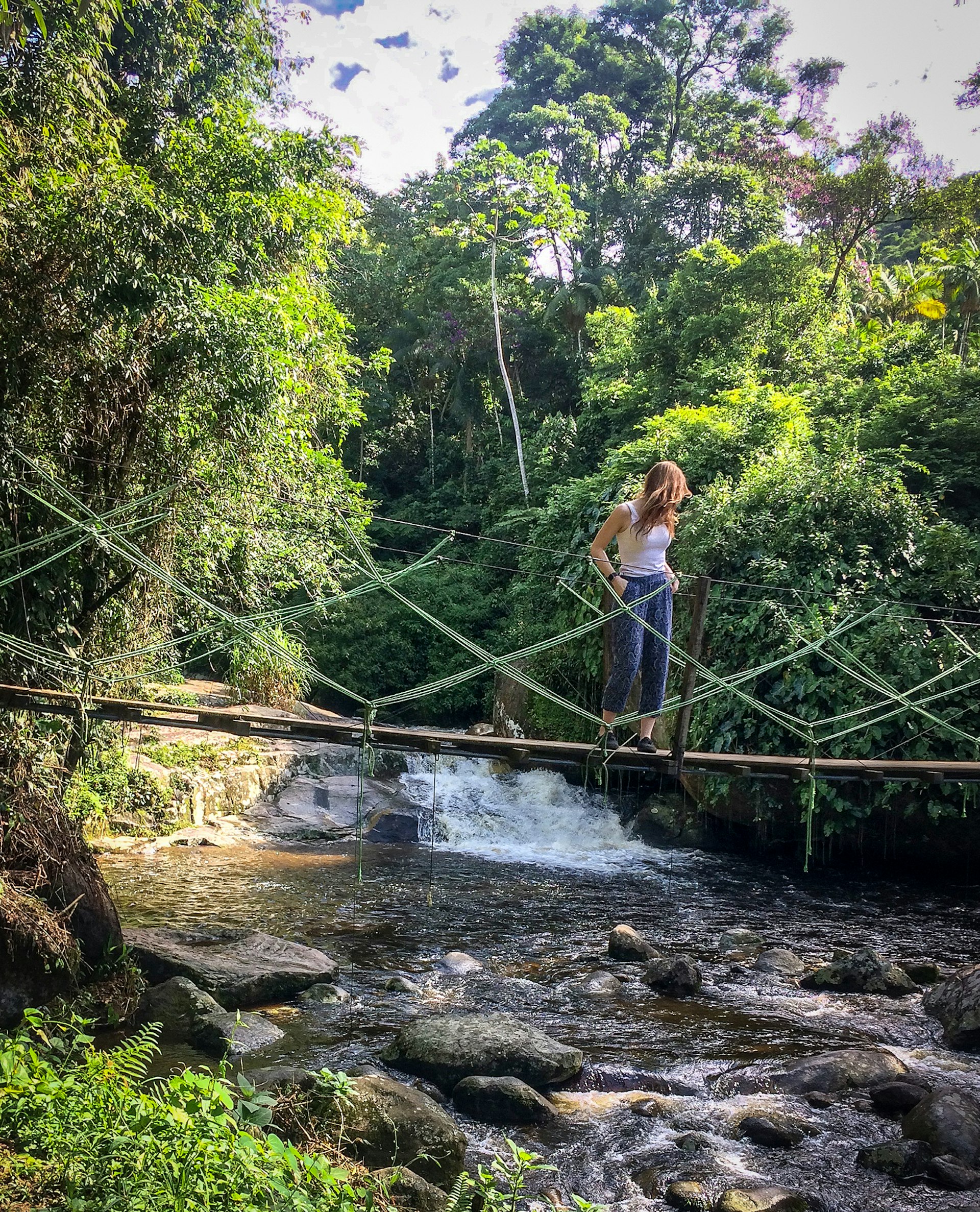 Woman stands on bridge over stream in Brazil