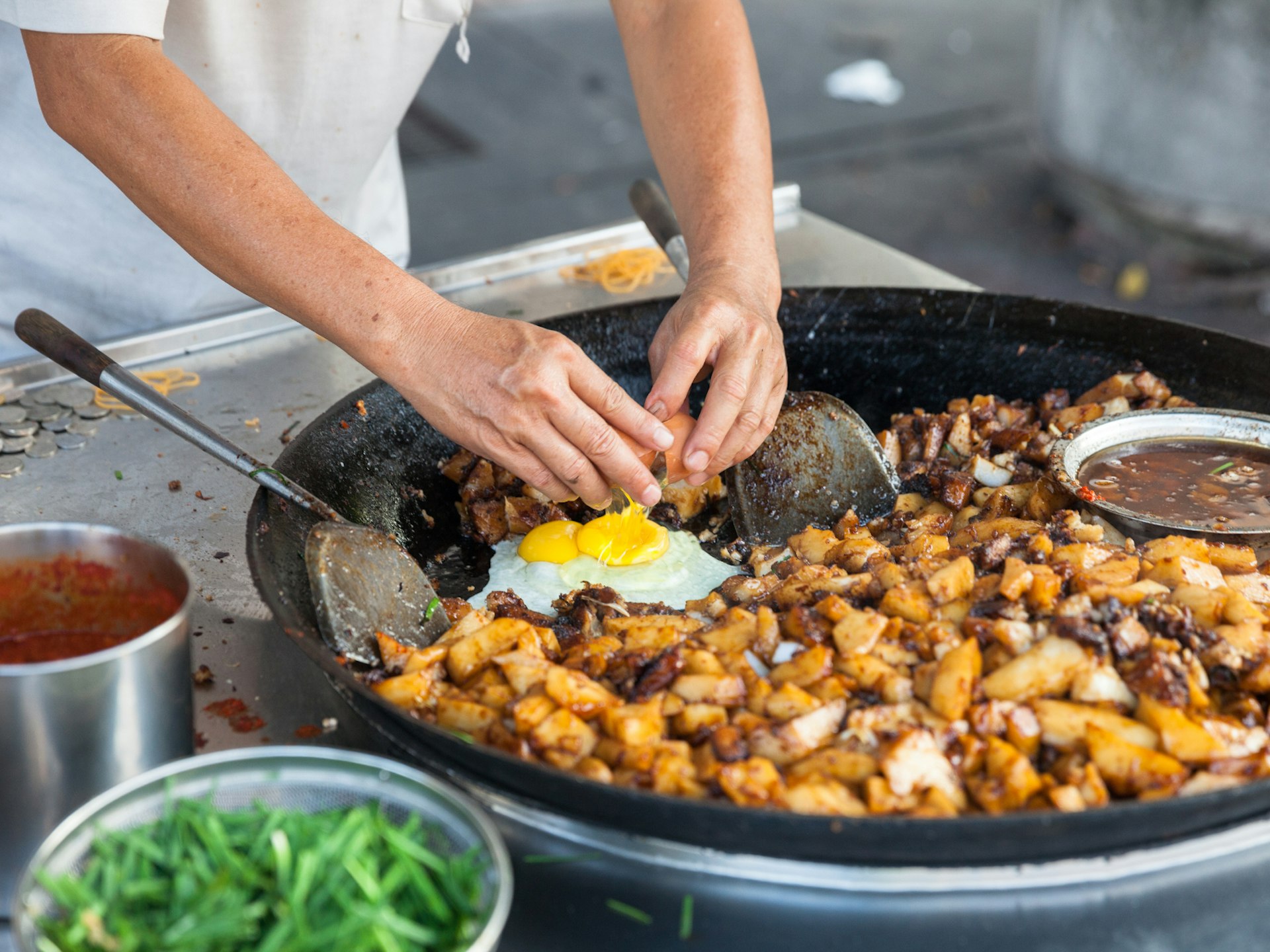 Street food vendor frying up potatoes and eggs