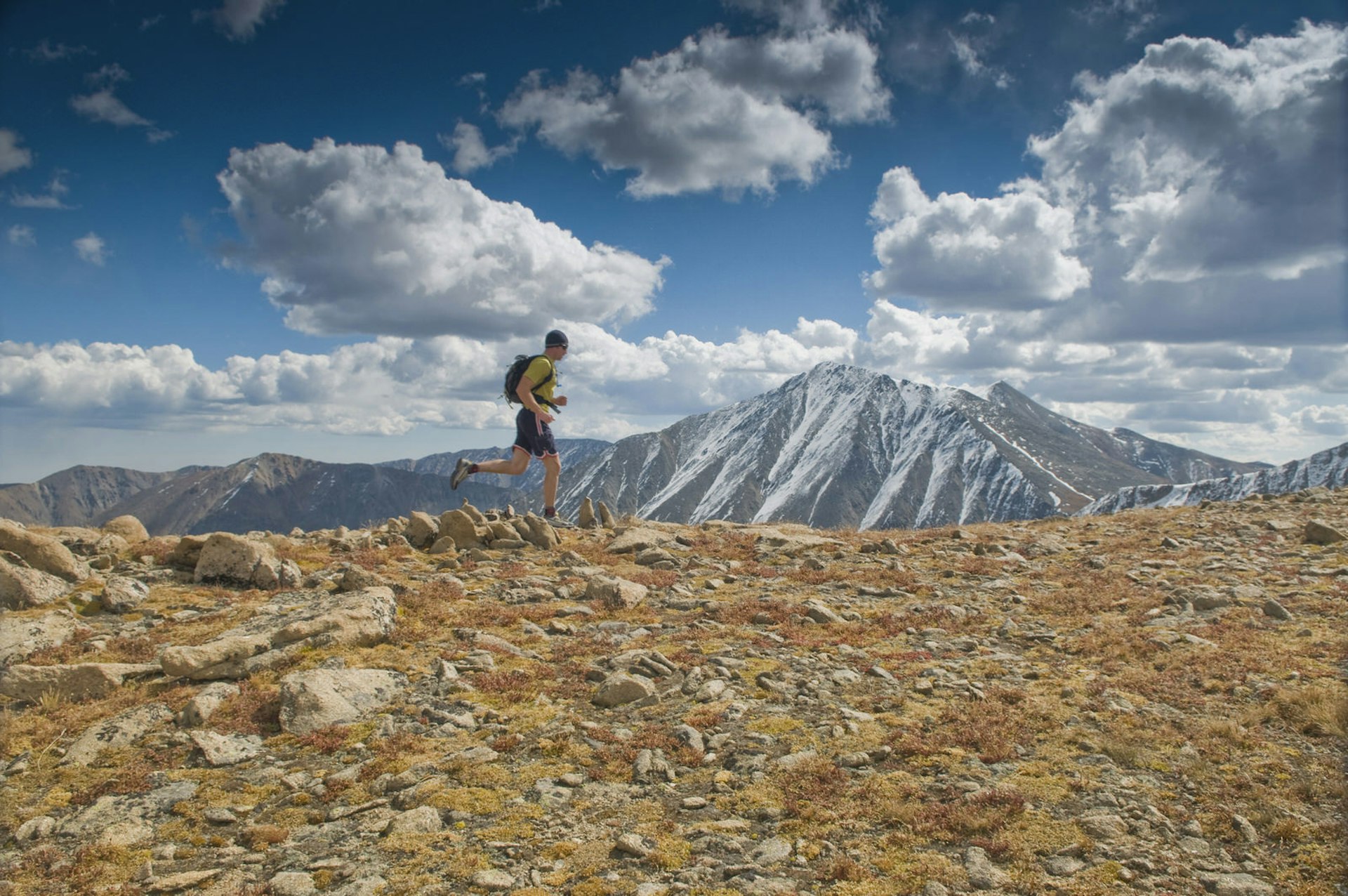A man runs along an alpine ridge on a crisp Fall day, with Torreys Peak (14,267 ft) in the background © Randall Levensaler / Getty Images