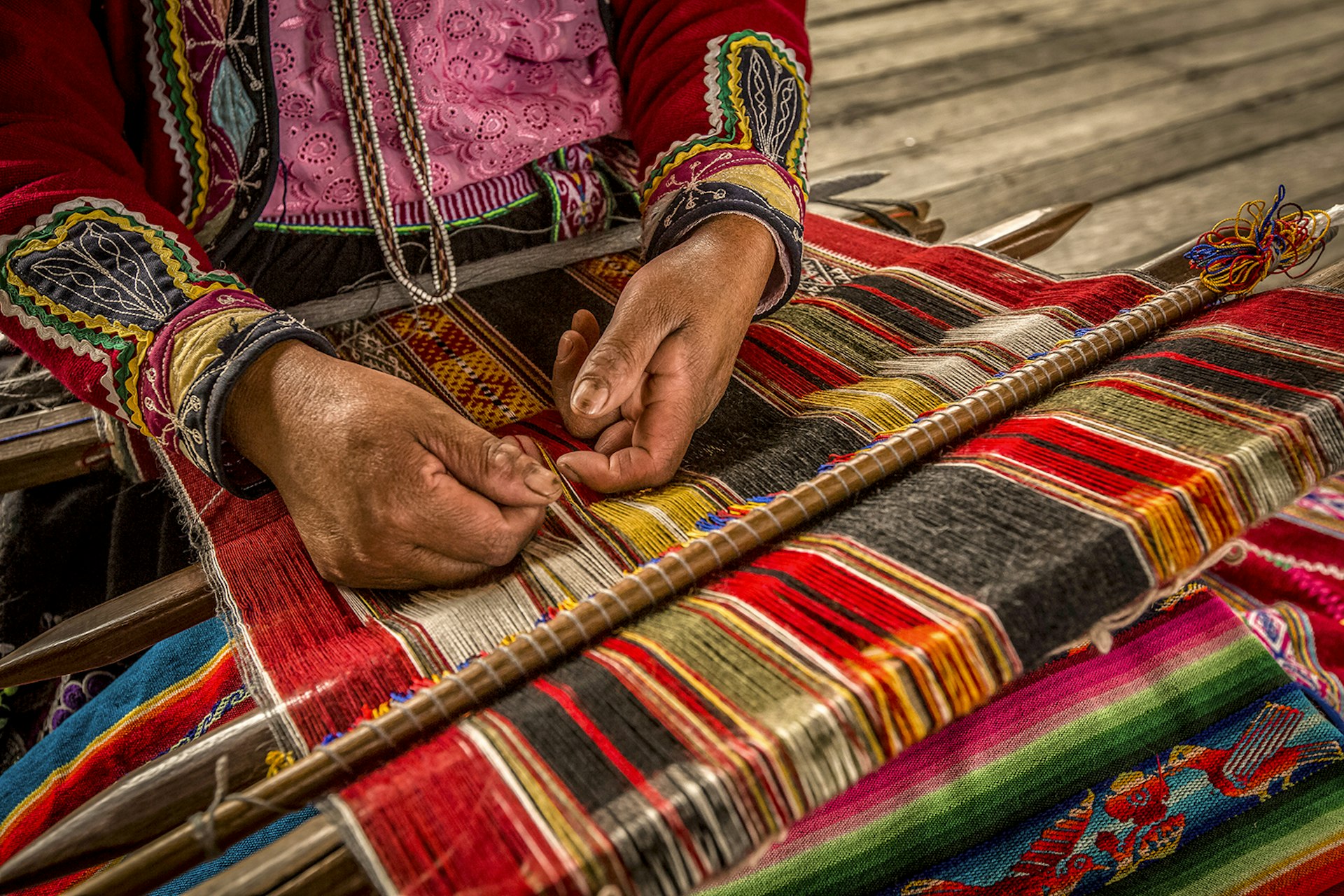 Closeup of woman's hands as she weaves blanket in Peru