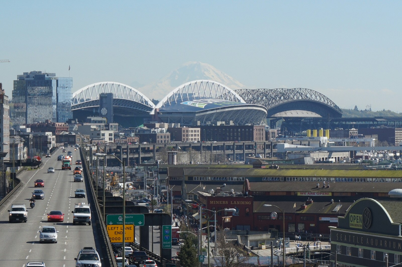 A freeway cuts through downtown Seattle, with sports stadiums and Mount Rainier in the background © Brendan Sainsbury / Lonely Planet
