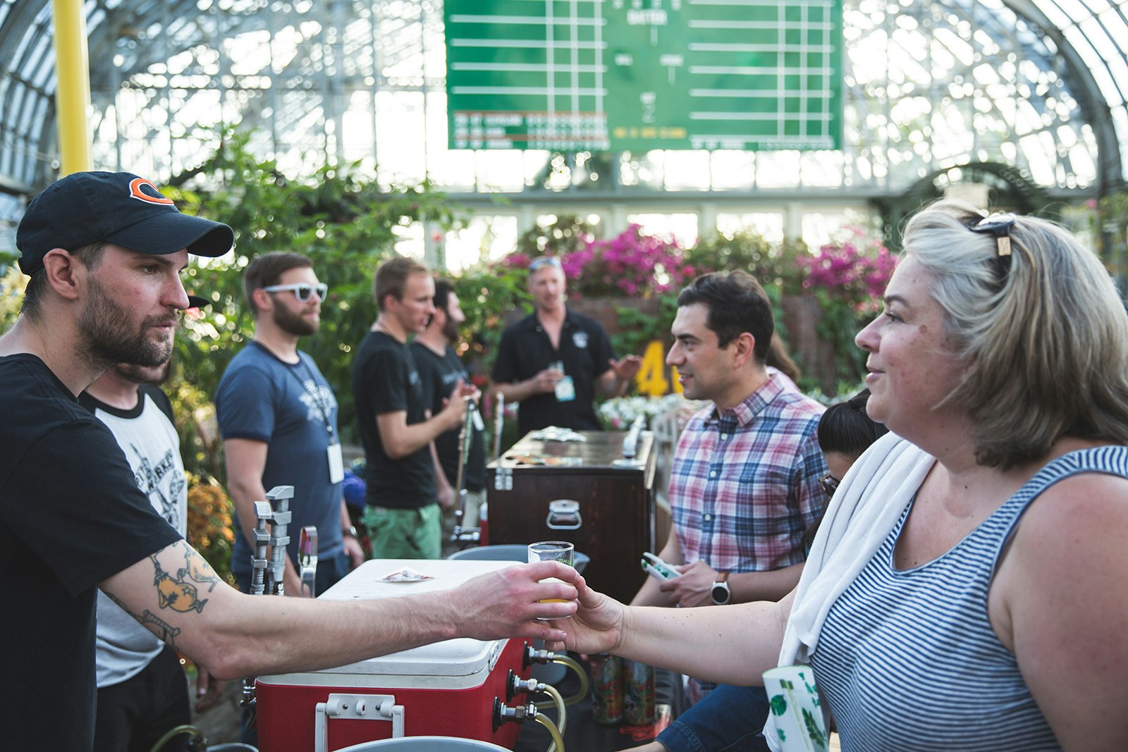 man hands woman a tasting glass of beer in Garfield Park Conservatory
