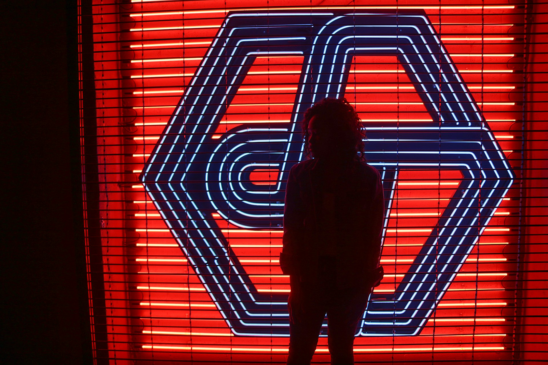 Woman in silhouette in front of a red and black neon sign © Ni'Kesia Pannell / Lonely Planet