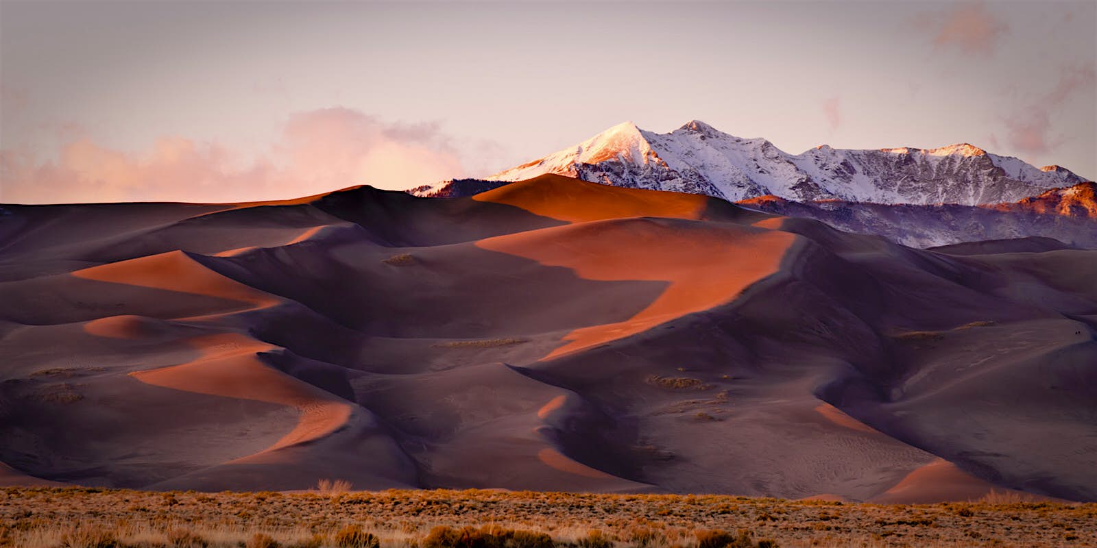 Features - Sand dunes and mountain peaks. Great Sand Dune National Park, Alamosa, Colorado. Sand dunes and mountain peaks are lit with evening light at Great Sand Dune National Park, Alamosa, Colorado © Dan Ballard / Getty Images