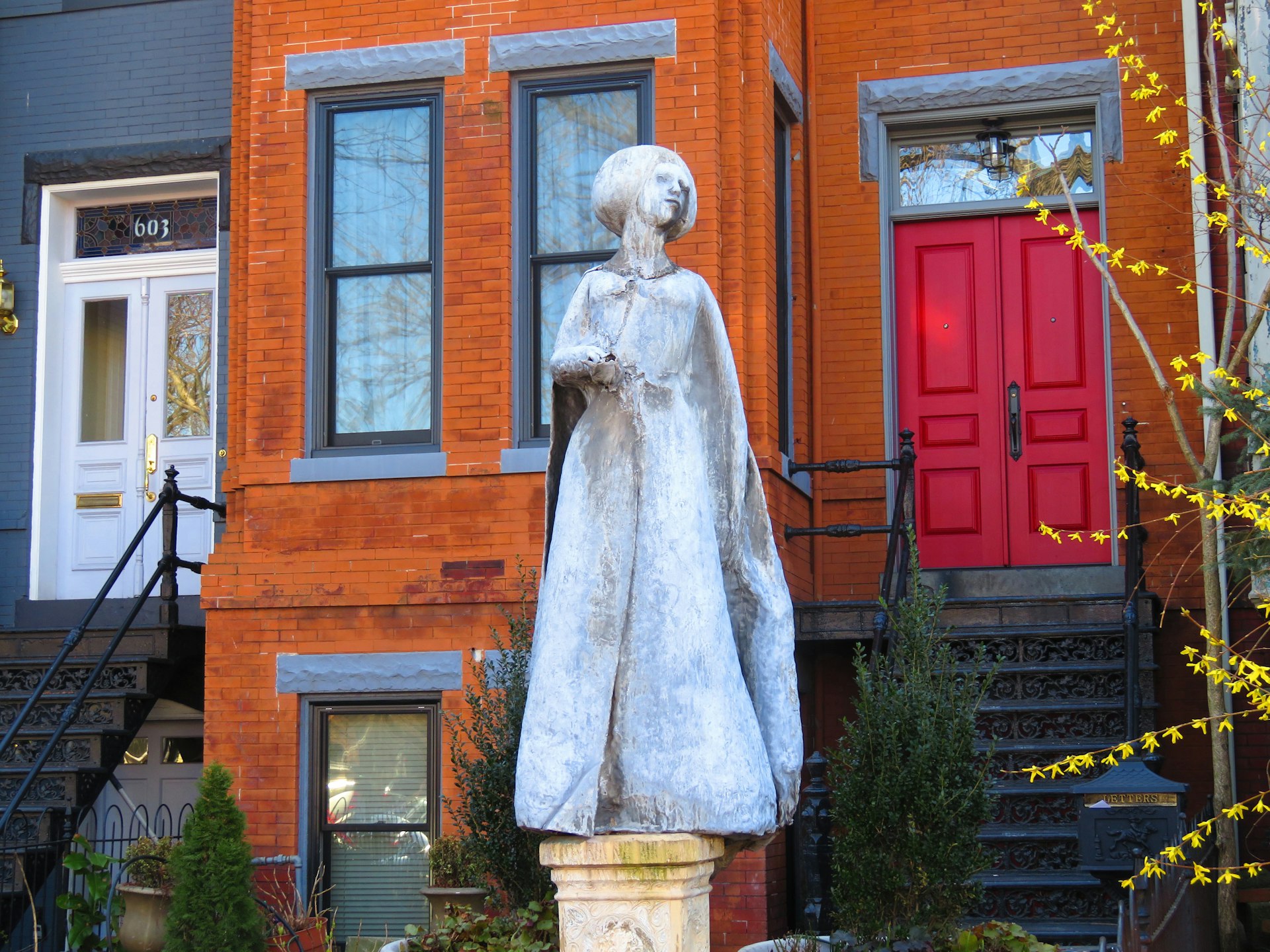 sculpture of young woman in front of rust orange row house in Washington, DC