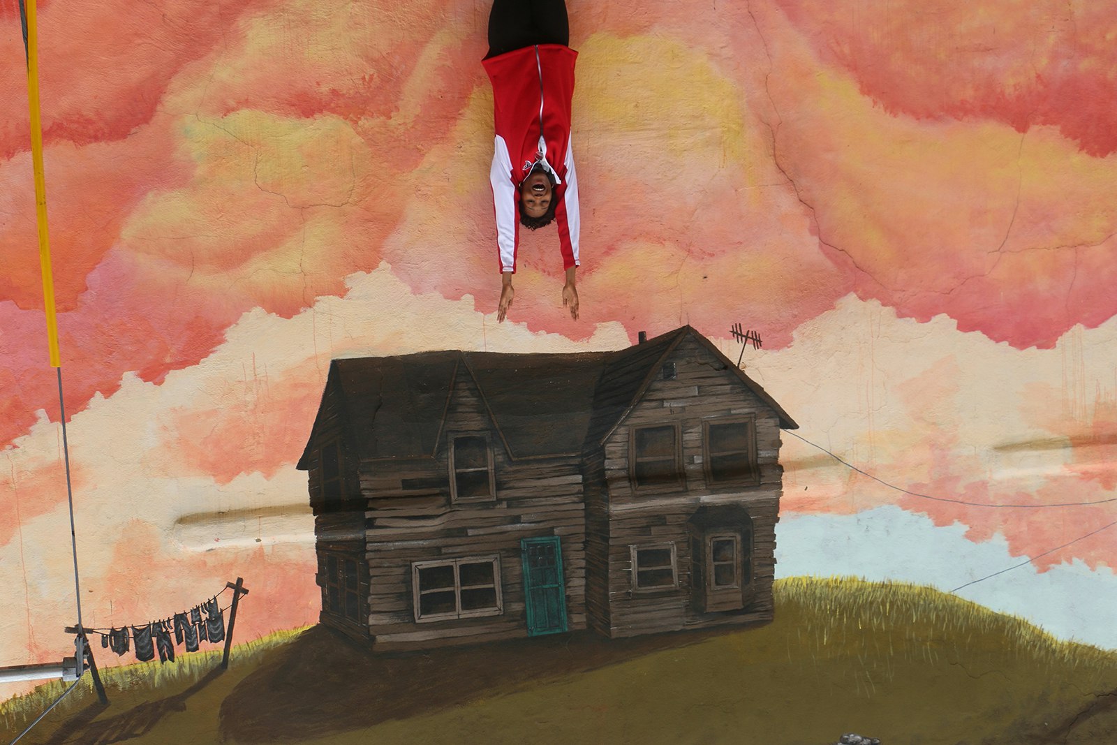 A woman appears to be upside-down over a painted house © Ni'Kesia Pannell / Lonely Planet