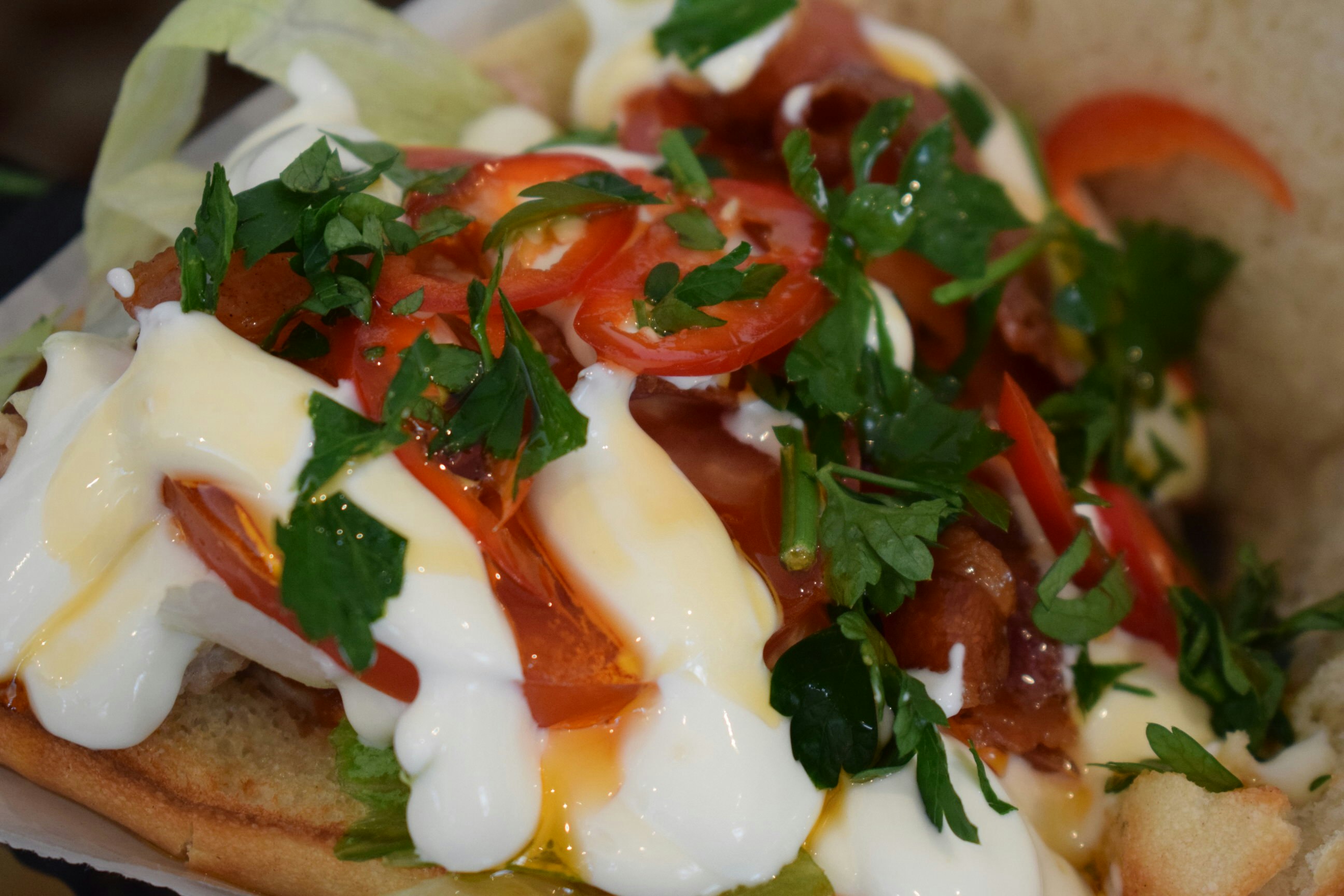 Close-up of an open sandwich made with cheese, tomatoes, chillies and parsley © Violetta Teetor