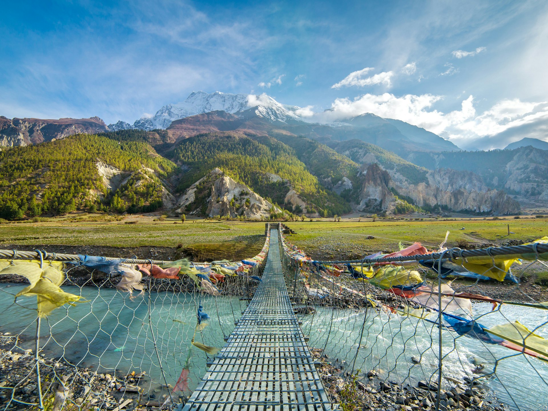 Suspension bridge, looking out to mountain scenery, with buddhist prayer flags on the Annapurna circuit trek in Nepal