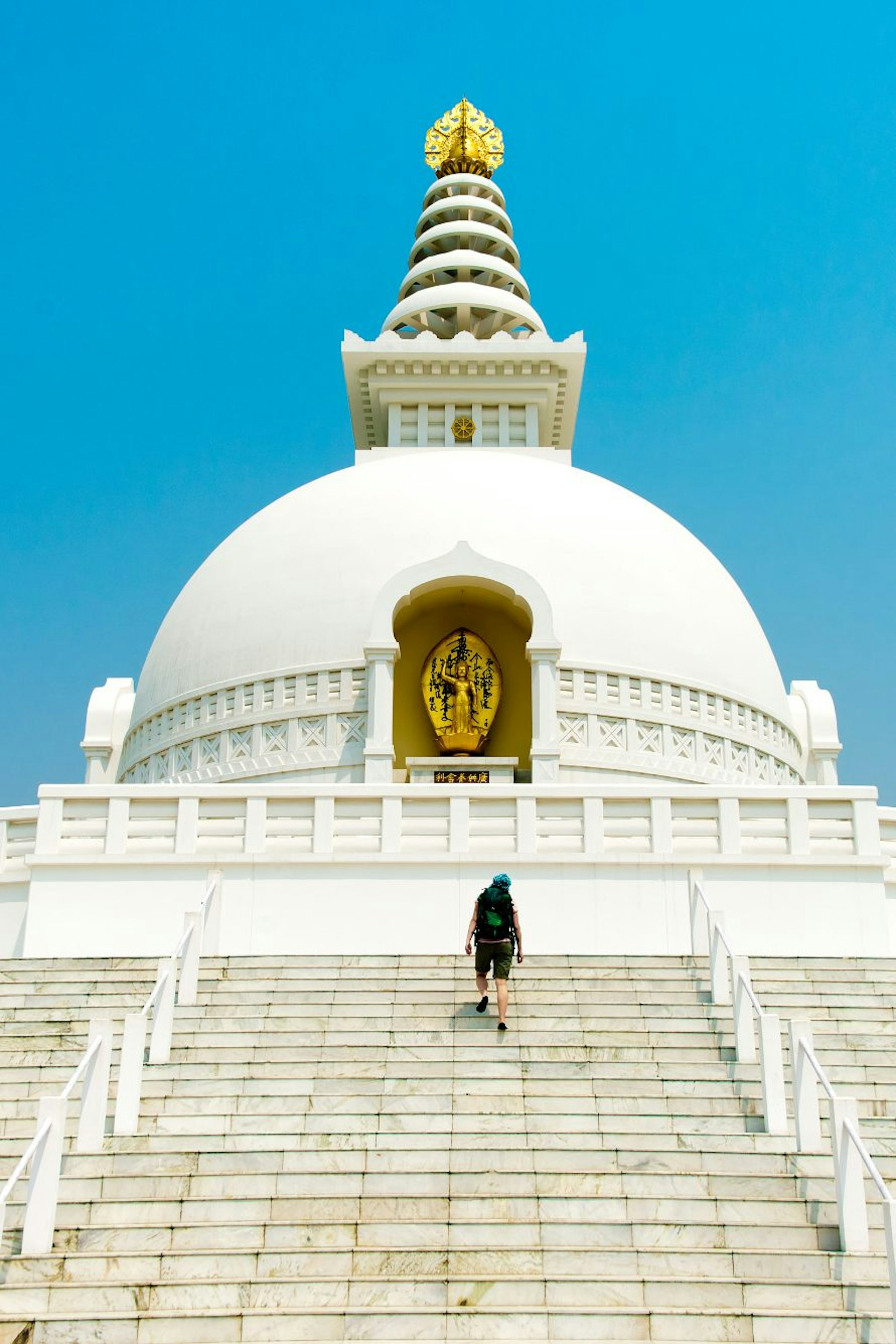 Man ascends stairs toward the gleaming-white World Peace Pagoda