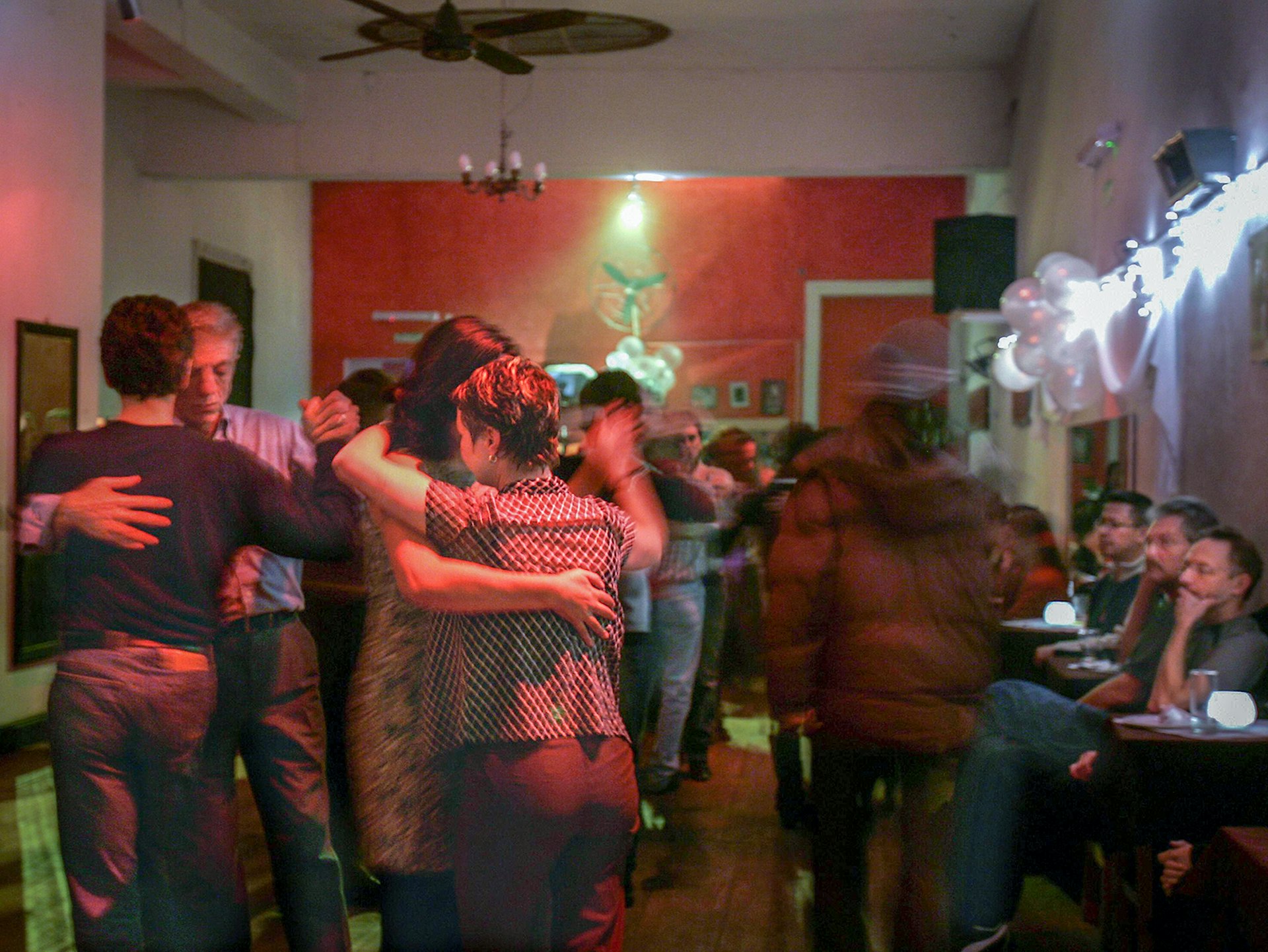 Gay couples dance the tango in a small room with a red wall© ALI BURAFI / Getty Images