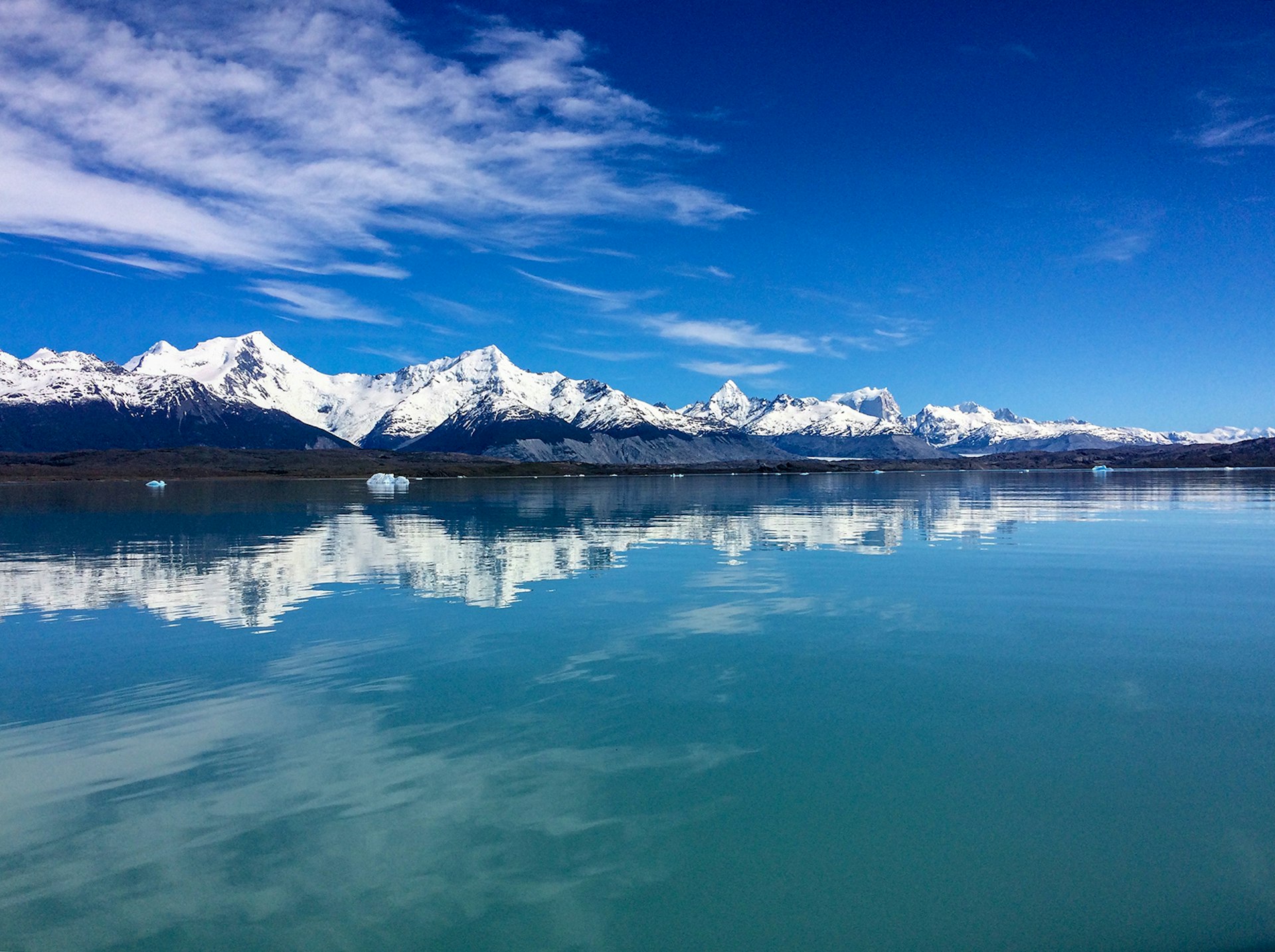 Mountains and blue sky reflect on a glassy lake
