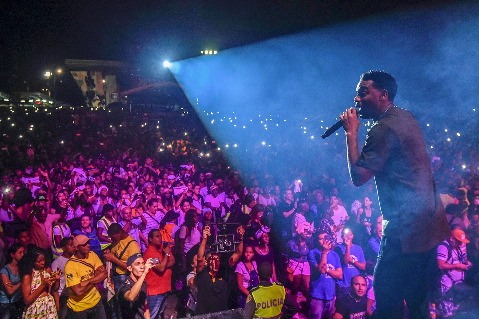 A man in a spotlight sings to a large crowd during the Petronio Alvarez festival