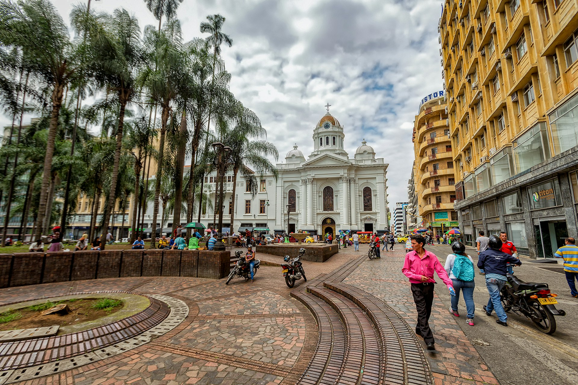 A man in a pink shirt walks through a colonial plaza in Cali