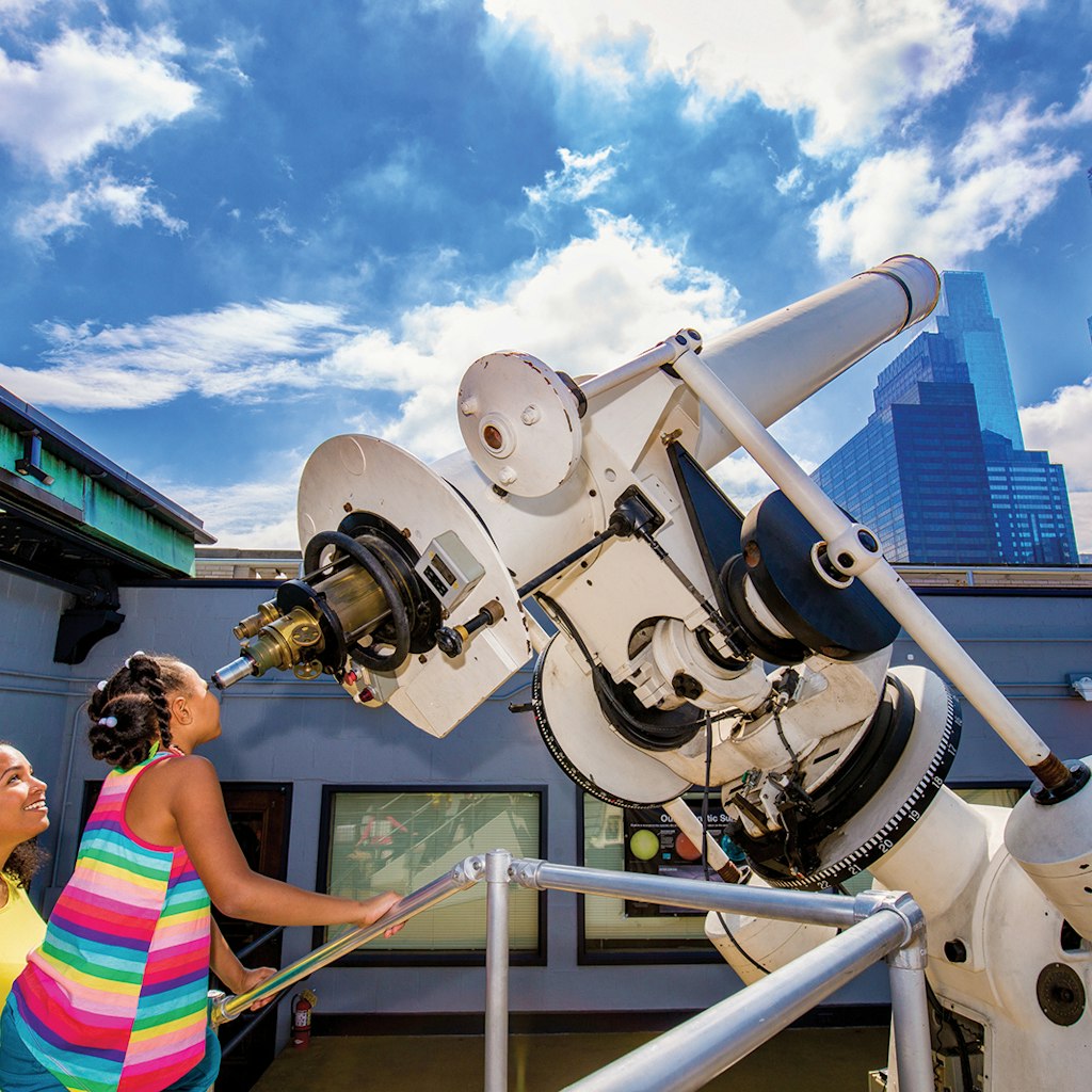 two children gaze into a telescope on a sunny day at the Franklin Museum J. Fusco for VISIT PHILADELPHIA®