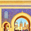 The golden arches of Fez's Blue Gate Bab Boujelud reveal life inside the medina; between the arches and gold trim, the large gate is decorated in delicate blue floral tiles.