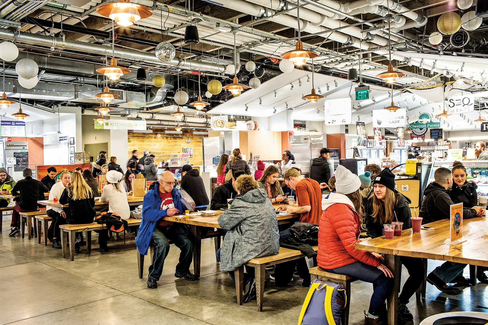 interior shot of a food hall, with people sitting at communal tables to dine © Adam DeTour / Lonely Planet