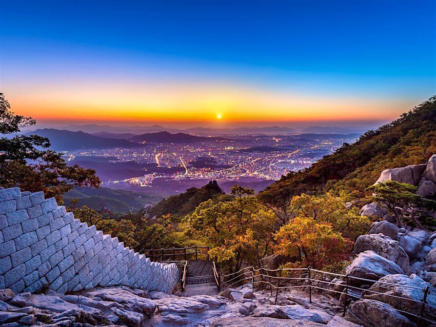 Features - Fabulous sunset views for free make the tough hike up Bukhansan worthwhile © Guitar photographer / Shutterstock The sun sets over Seoul as the city lights come on, while a rocky path leads down the mountain directly in front. Fabulous sunset views for free make the tough hike up Bukhansan worthwhile © Guitar photographer / Shutterstock