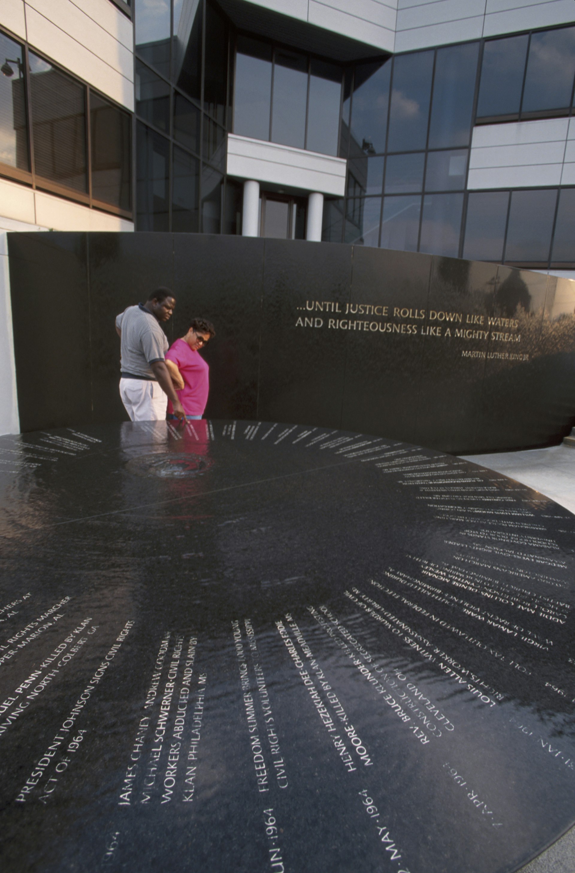 Man and woman in front of large granite Civil Rights Memorial in Montgomery, Alabama © Jeff Greenberg / Getty Images
