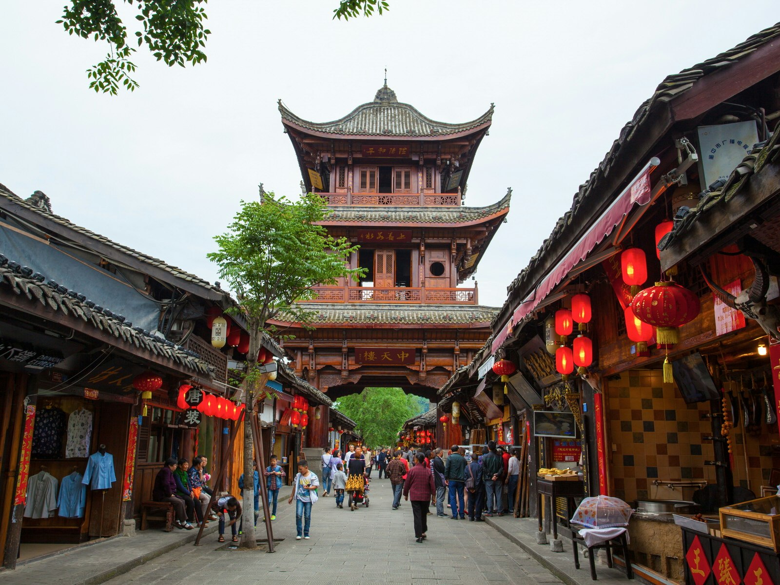 A historic Chinese street lined by red lanterns with a multi-storey traditional gate with upturned eaves. Historic, chilled-out Langzhong is a good place to discover ancient Chinese culture and literature © Meiqianbao / Shutterstock
