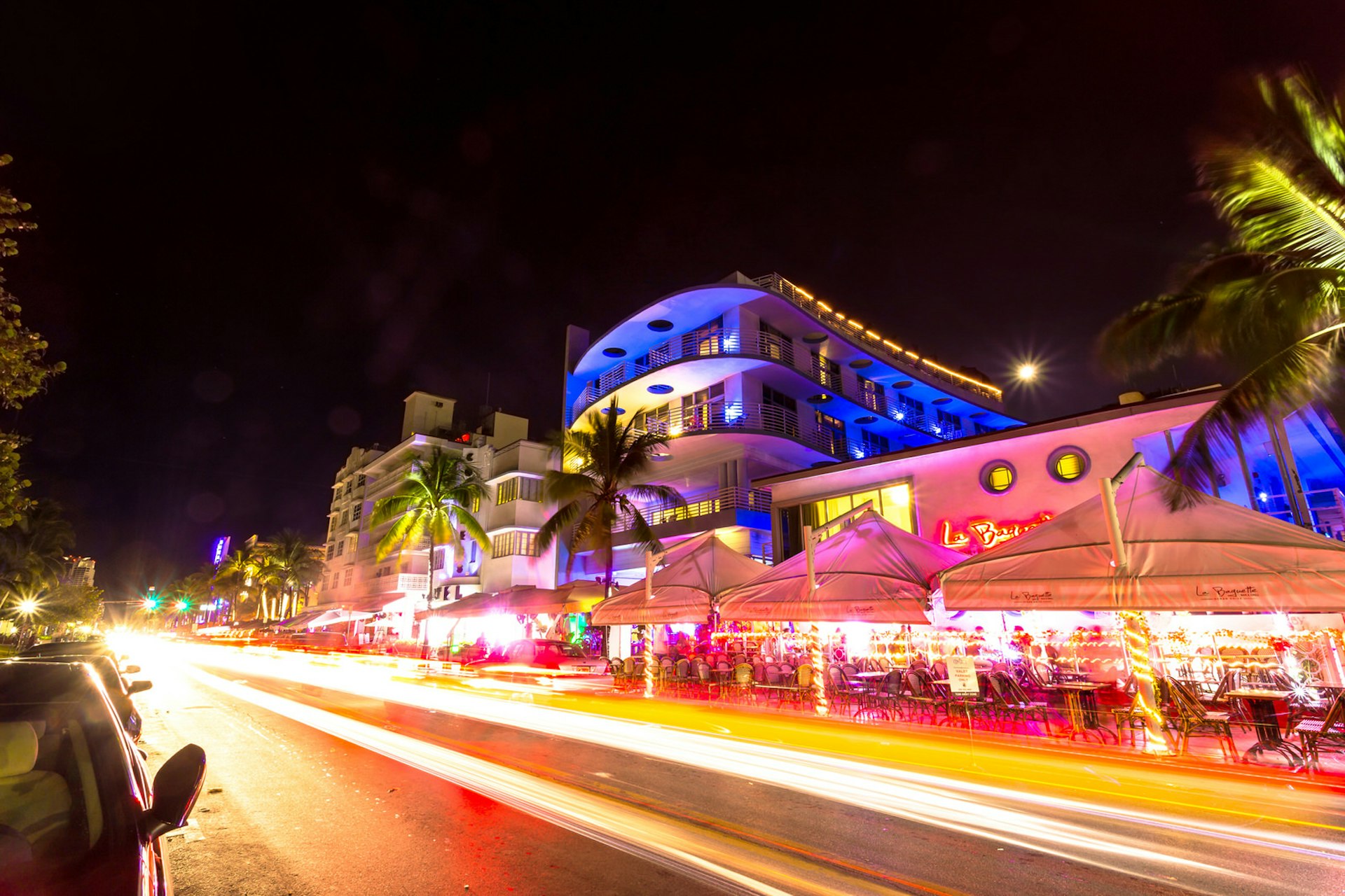 Ocean Drive scene at night with neon lights, palm trees, cars and people having fun © Pola Damonte / Getty Images
