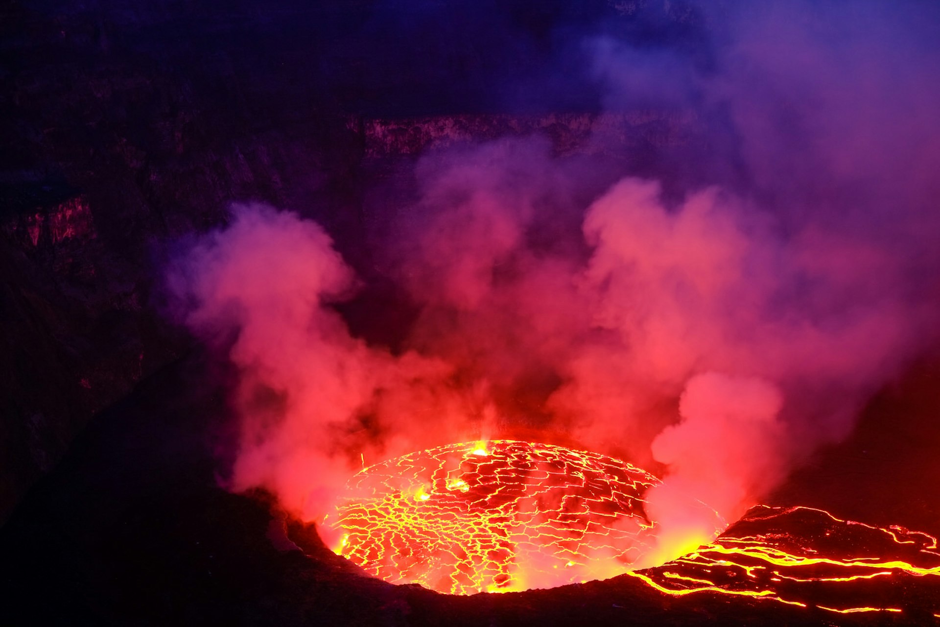 Nyiragongo's lava lake smokes and glows red in the evening darkness.
