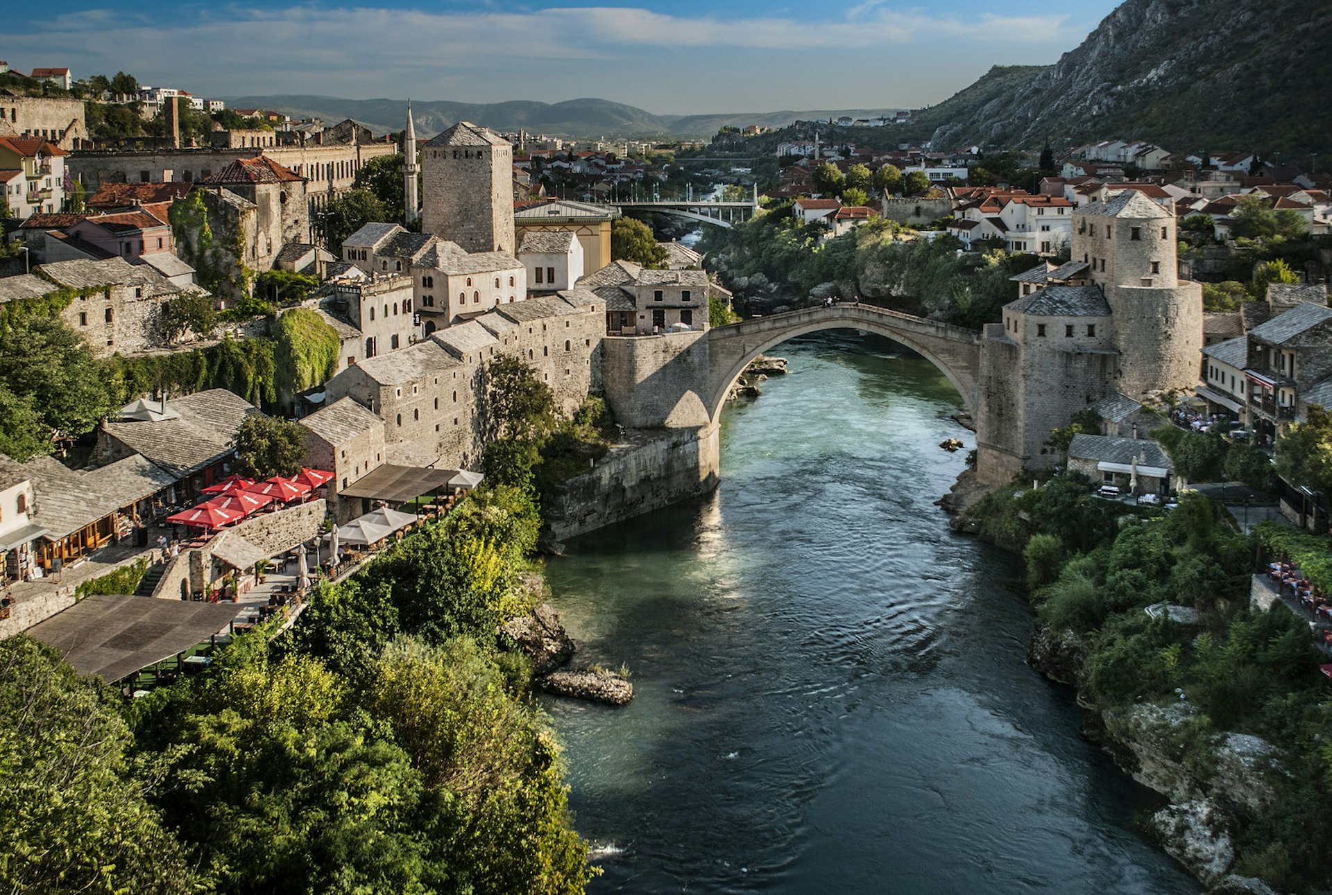 The city of Mostar, with stone buildings lining the river and its very high, arched stone bridge in the centre