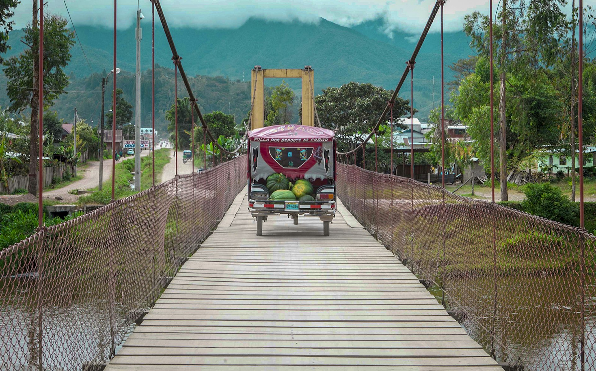 A cart with watermelons int he back goes across a wooden bridge © Erick Andía / Lonely Planet