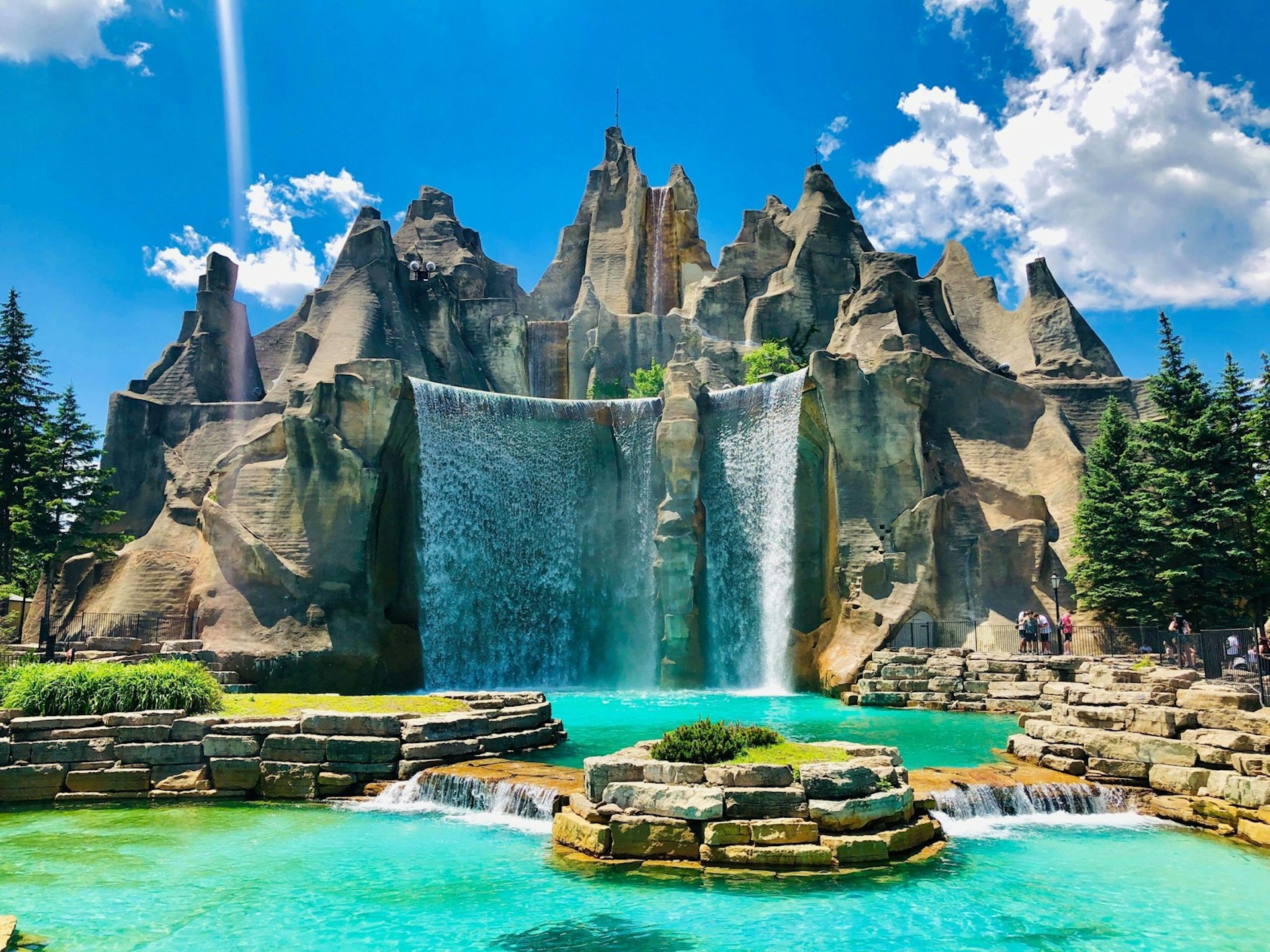 A large waterfall pools into a large man-made stone enclosed structure; North America's top amusement parks  